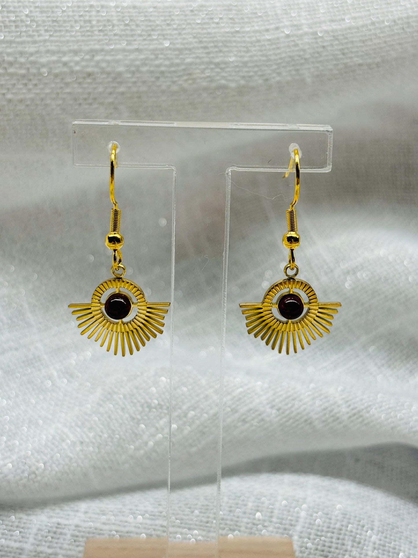 Boucles d'oreille ALLY, avec pierre de Grenat, exposées sur un fond en lin.