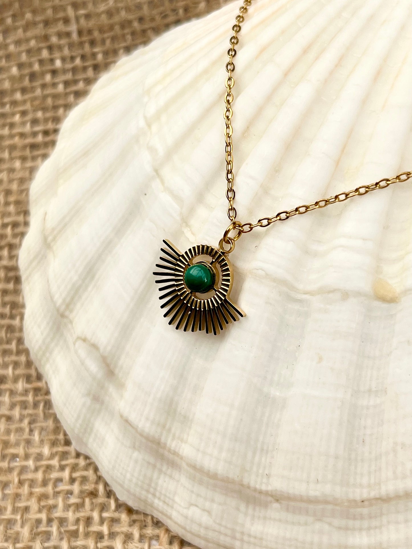 Collier ALLY, avec pierre de Malachite, exposé sur un coquillage.