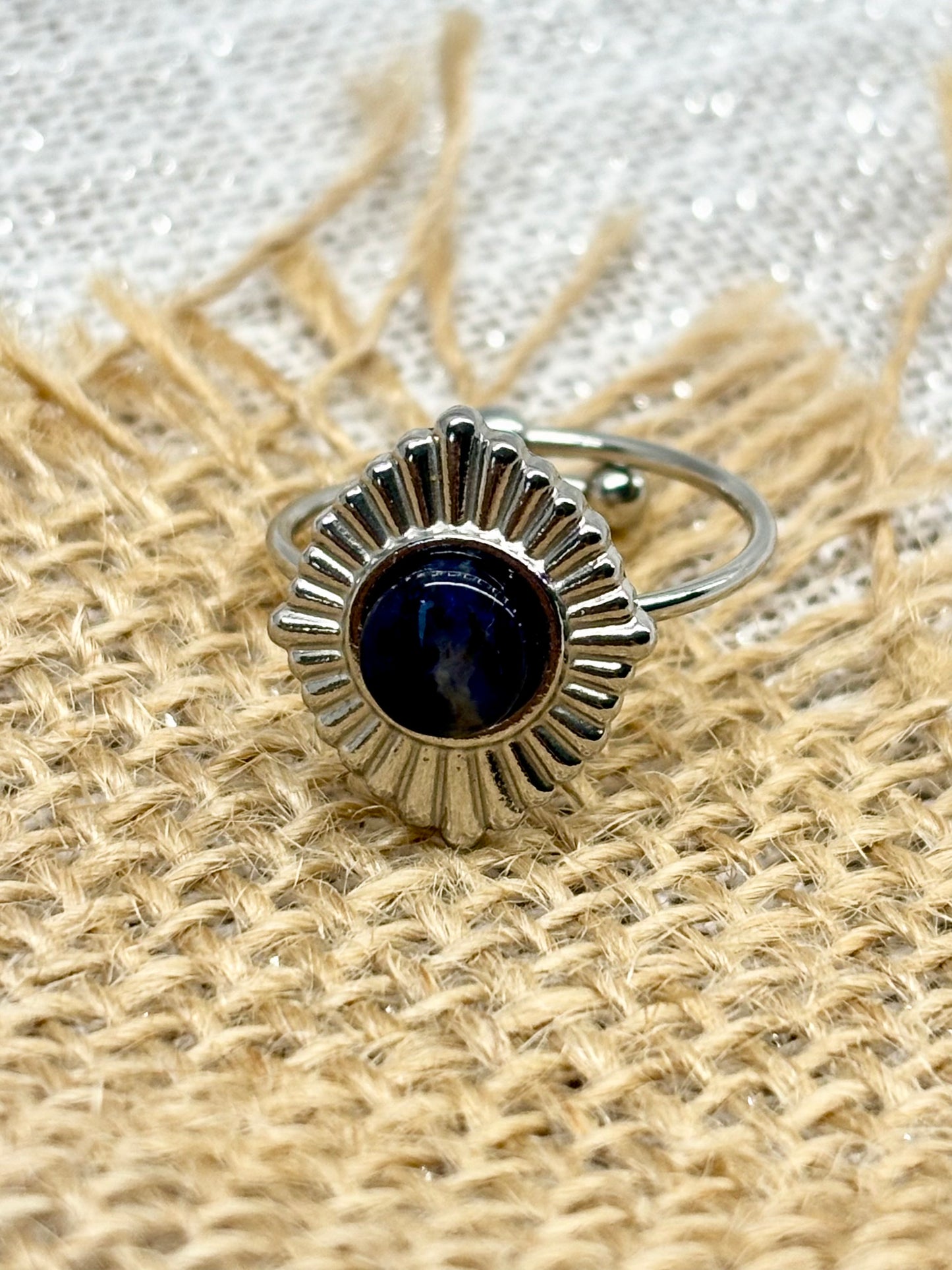 Bague ALYSÉE, de couleur Argent avec pierre de Sodalite, exposée sur un fond en toile de jute et lin.