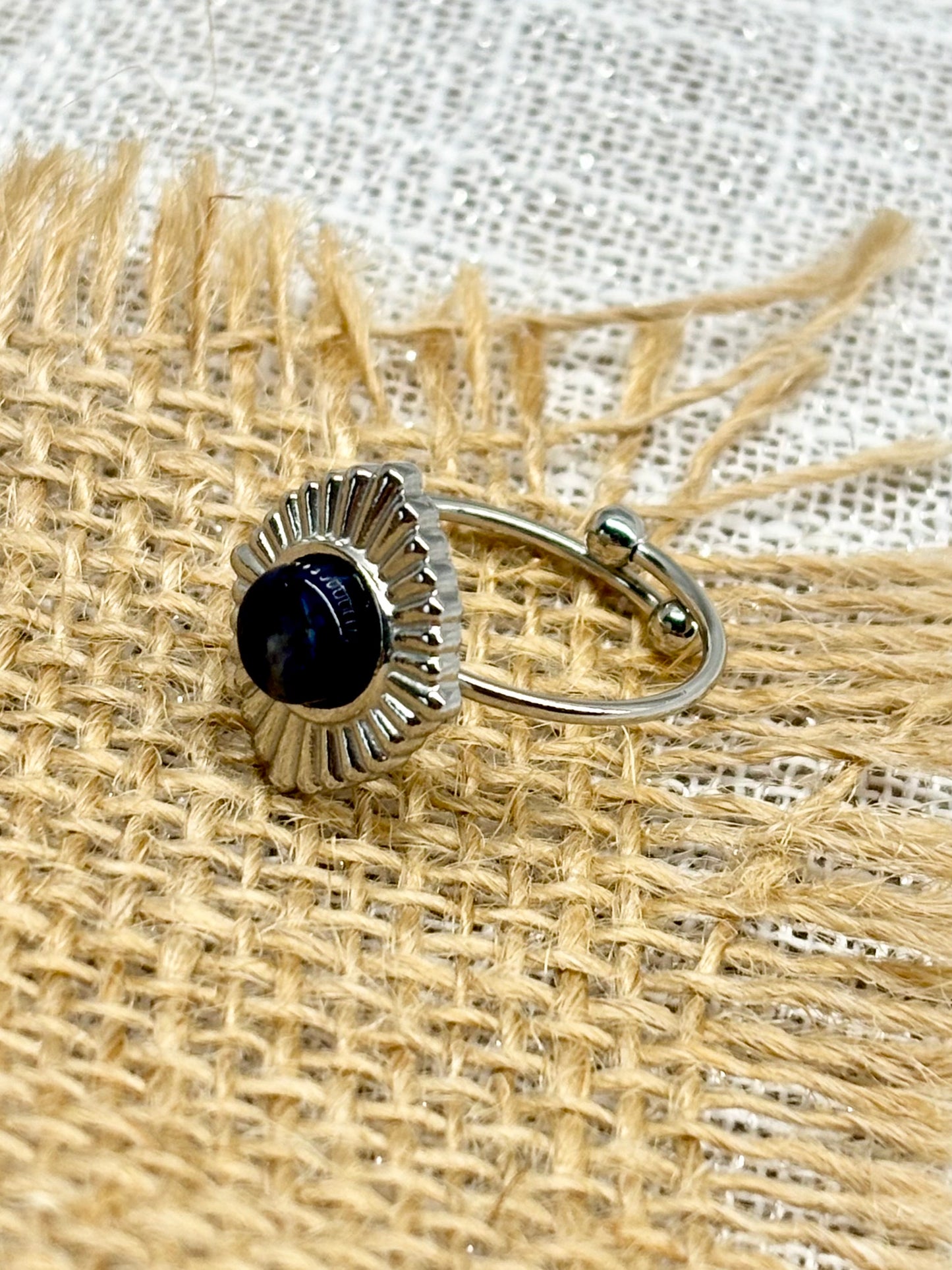 Bague ALYSÉE, de couleur Argent avec pierre de Sodalite, exposée sur un fond en toile de jute et lin.