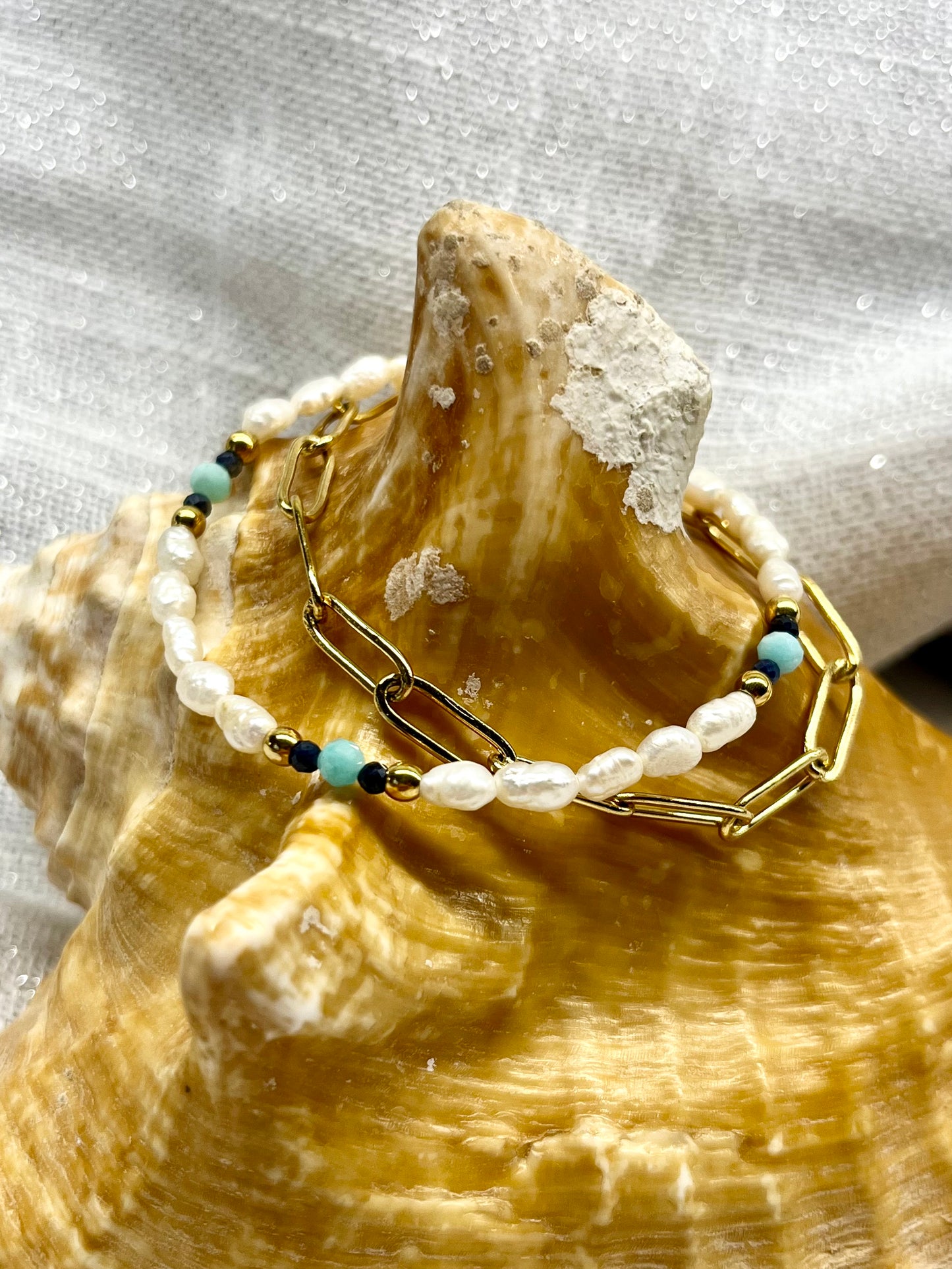 Bracelet ARIANA, avec pierre d'Amazonite, Saphir et Perle de Culture, exposé sur un coquillage.