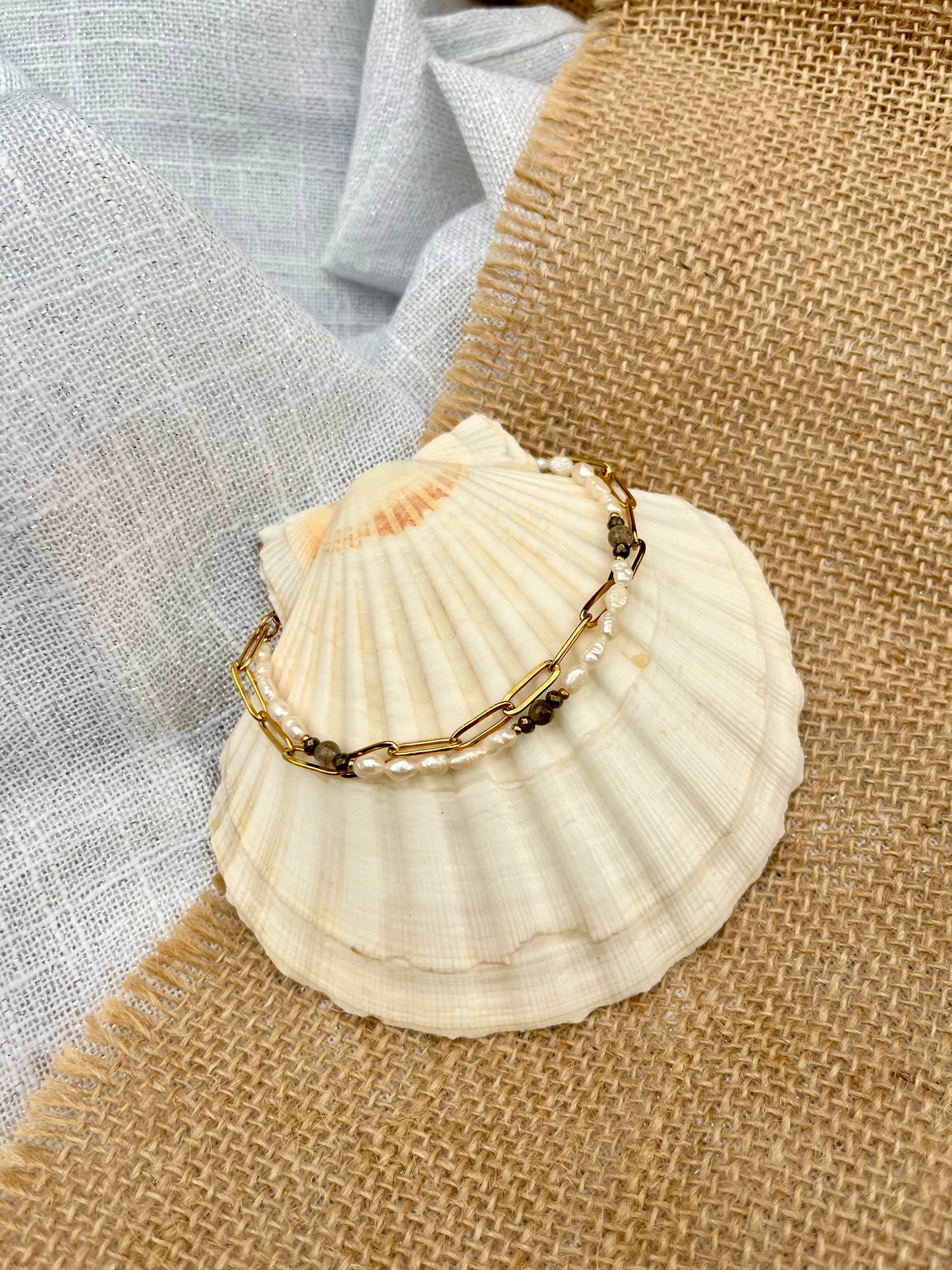 Bracelet ARIANA, avec pierres de Labradorite, Pyrite et Perles de Culture, exposé sur un coquillage.