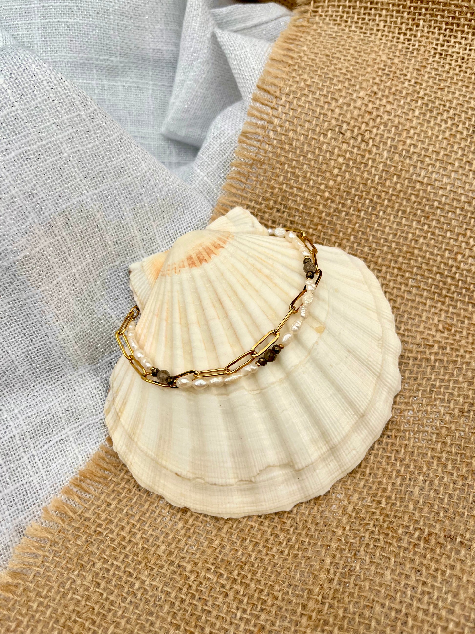 Bracelet ARIANA, avec pierres de Labradorite, Pyrite et Perles de Culture, exposé sur un coquillage.