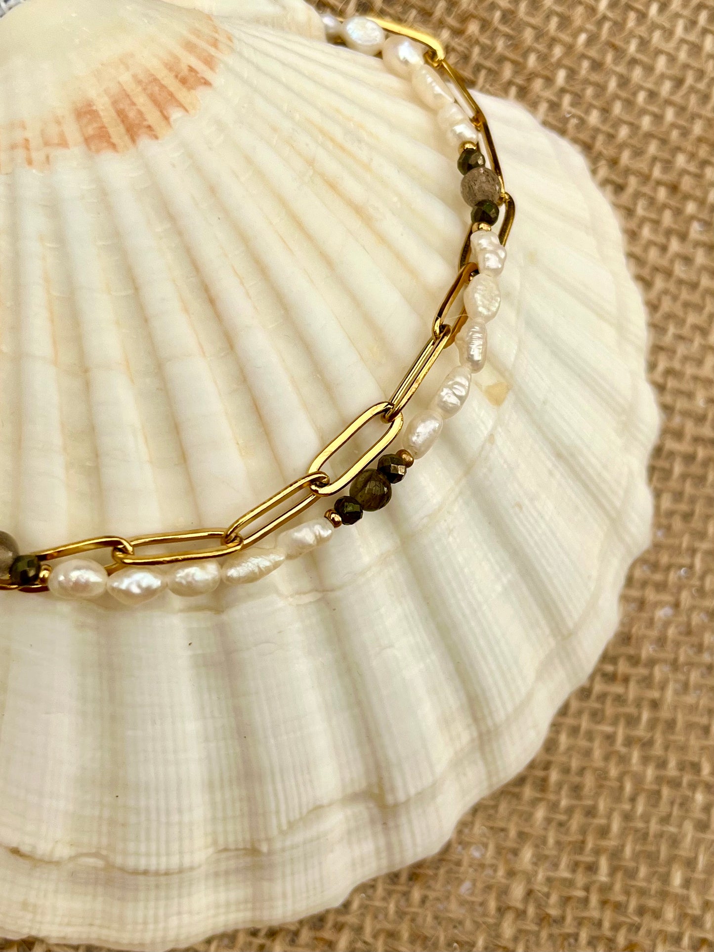 Bracelet ARIANA, avec pierres de Labradorite, Pyrite et Perles de Culture, exposé sur un coquillage.