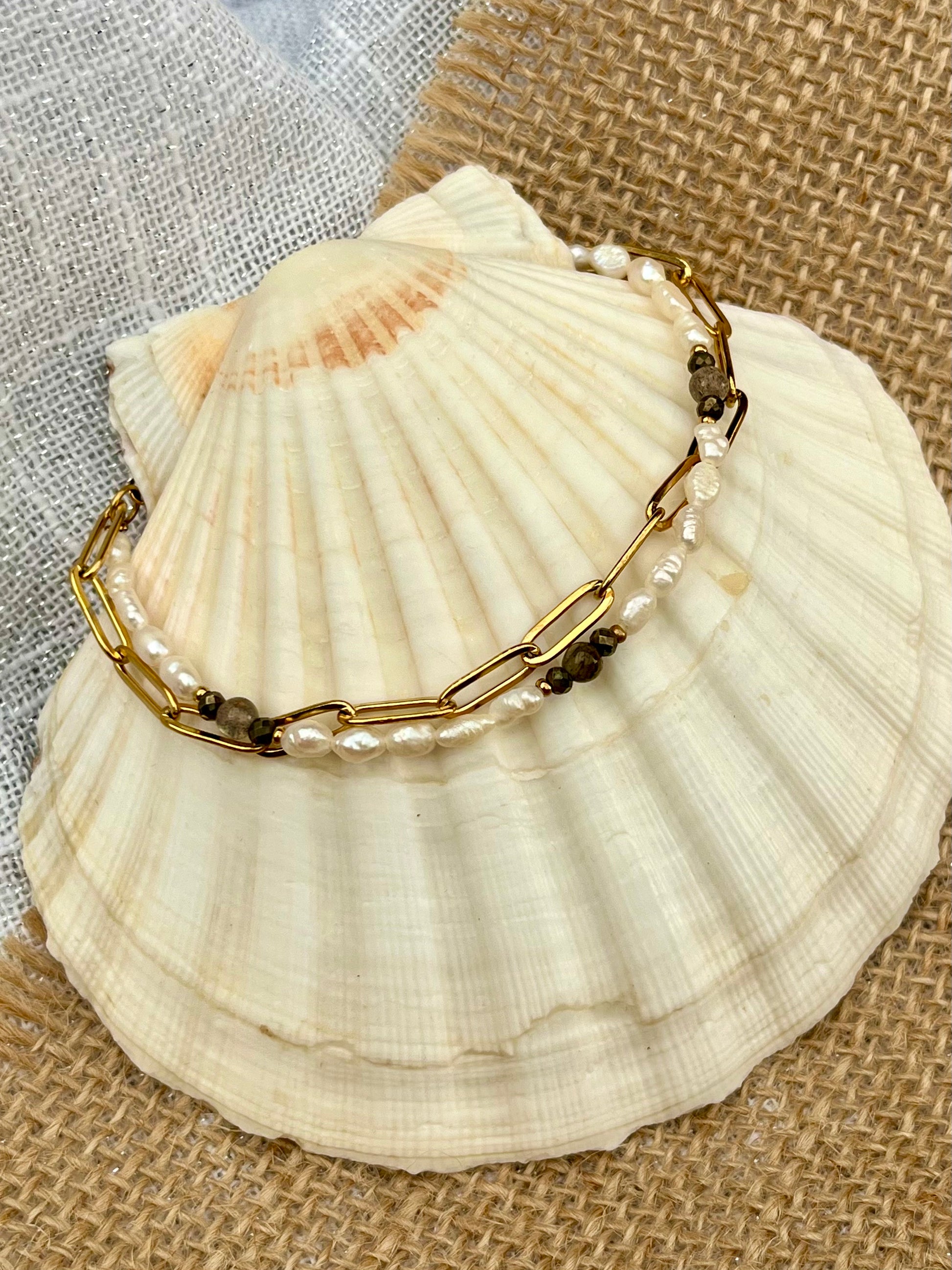 Bracelet ARIANA, avec pierres de Labradorite, Pyrite et Perles de Culture, exposé sur un coquillage.