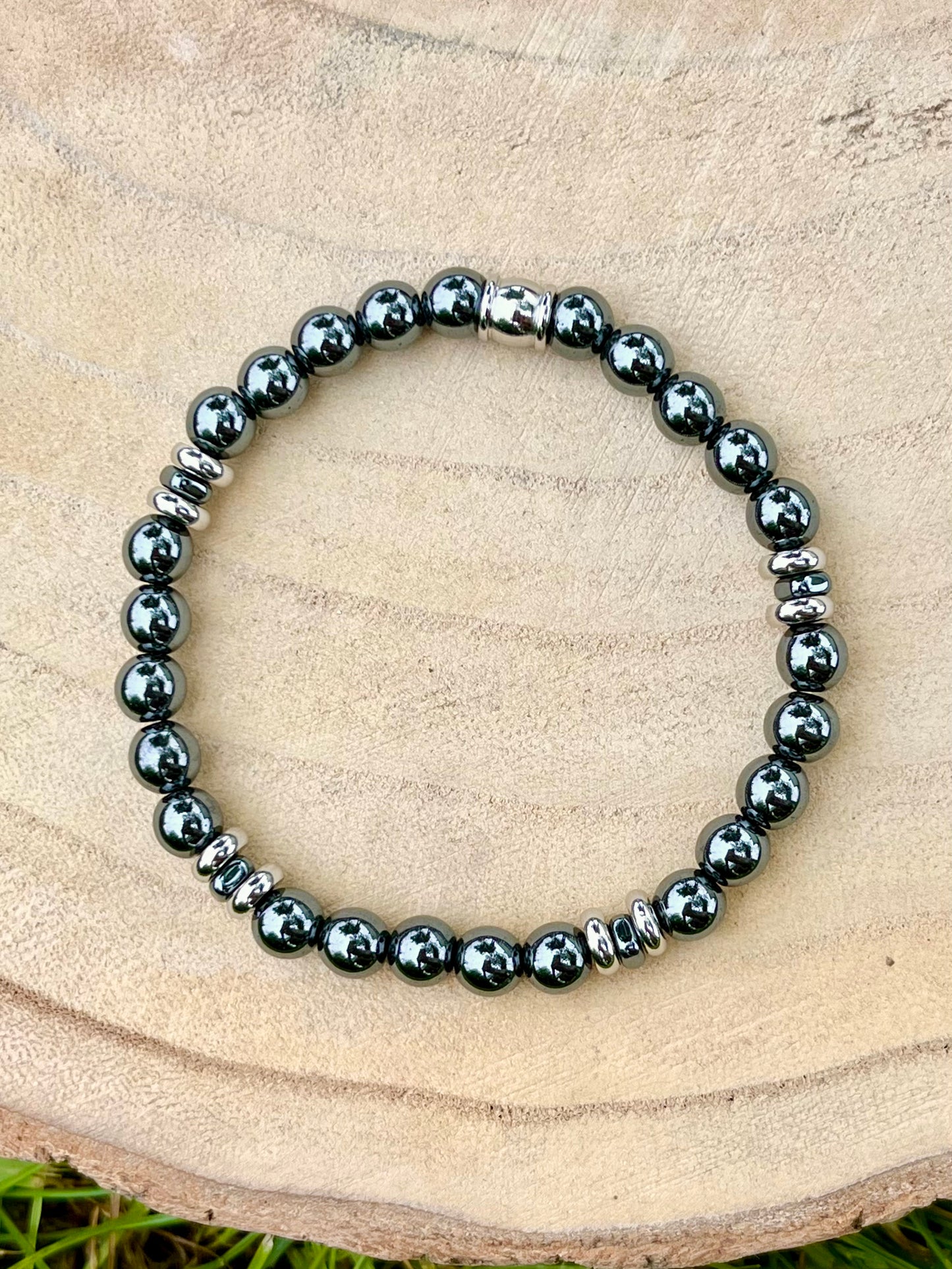 Bracelet CAMILLE, avec pierres d'Hématite, exposé sur un rondin de bois.