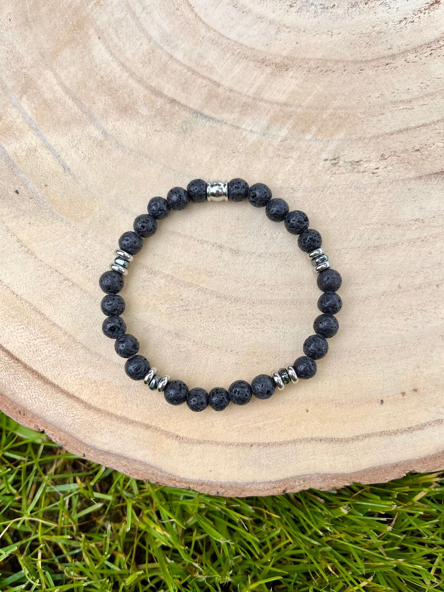 Bracelet CAMILLE, avec pierres de Lave, exposé sur un rondin de bois.