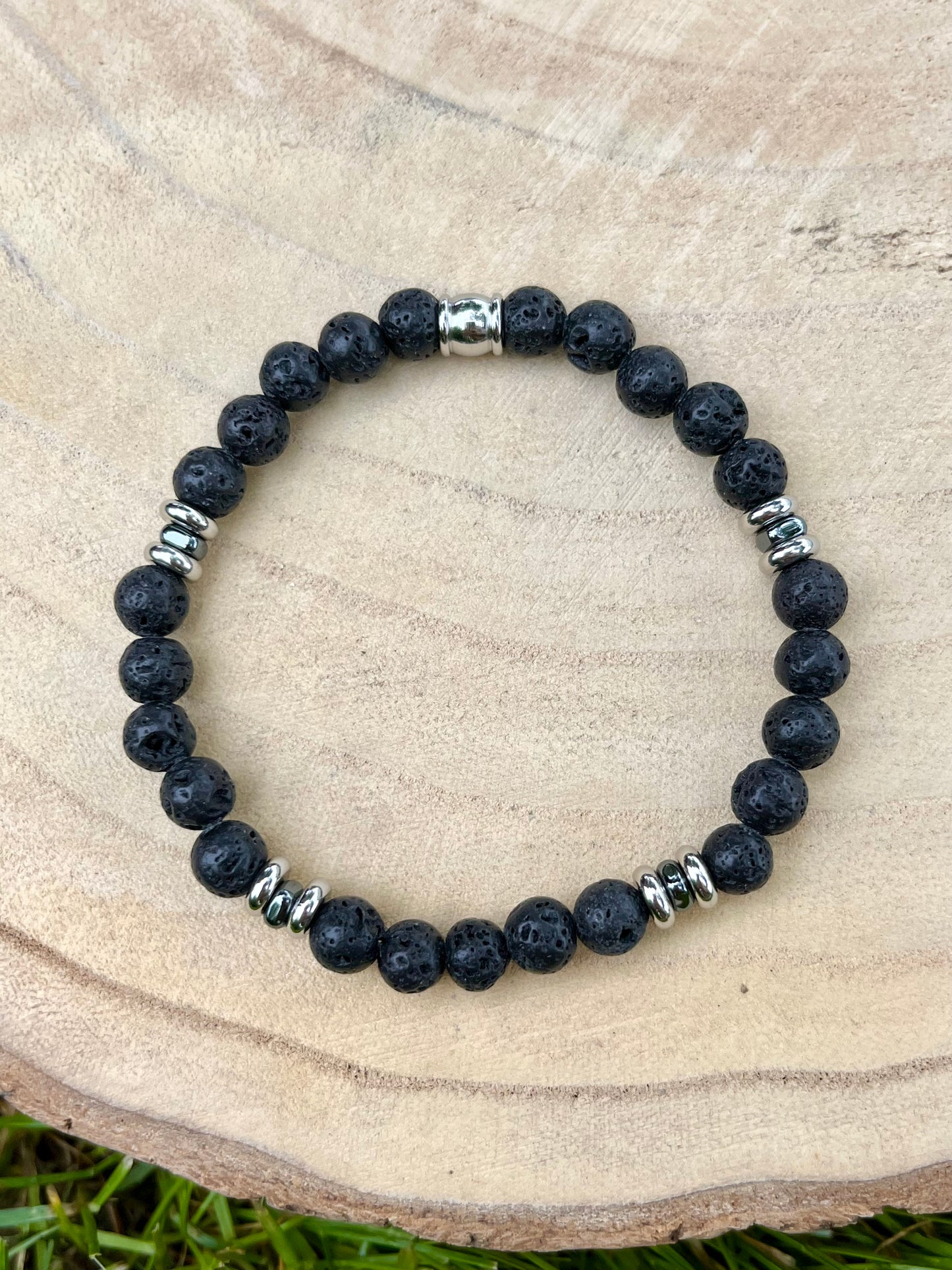 Bracelet CAMILLE, avec pierres de Lave, exposé sur un rondin de bois.