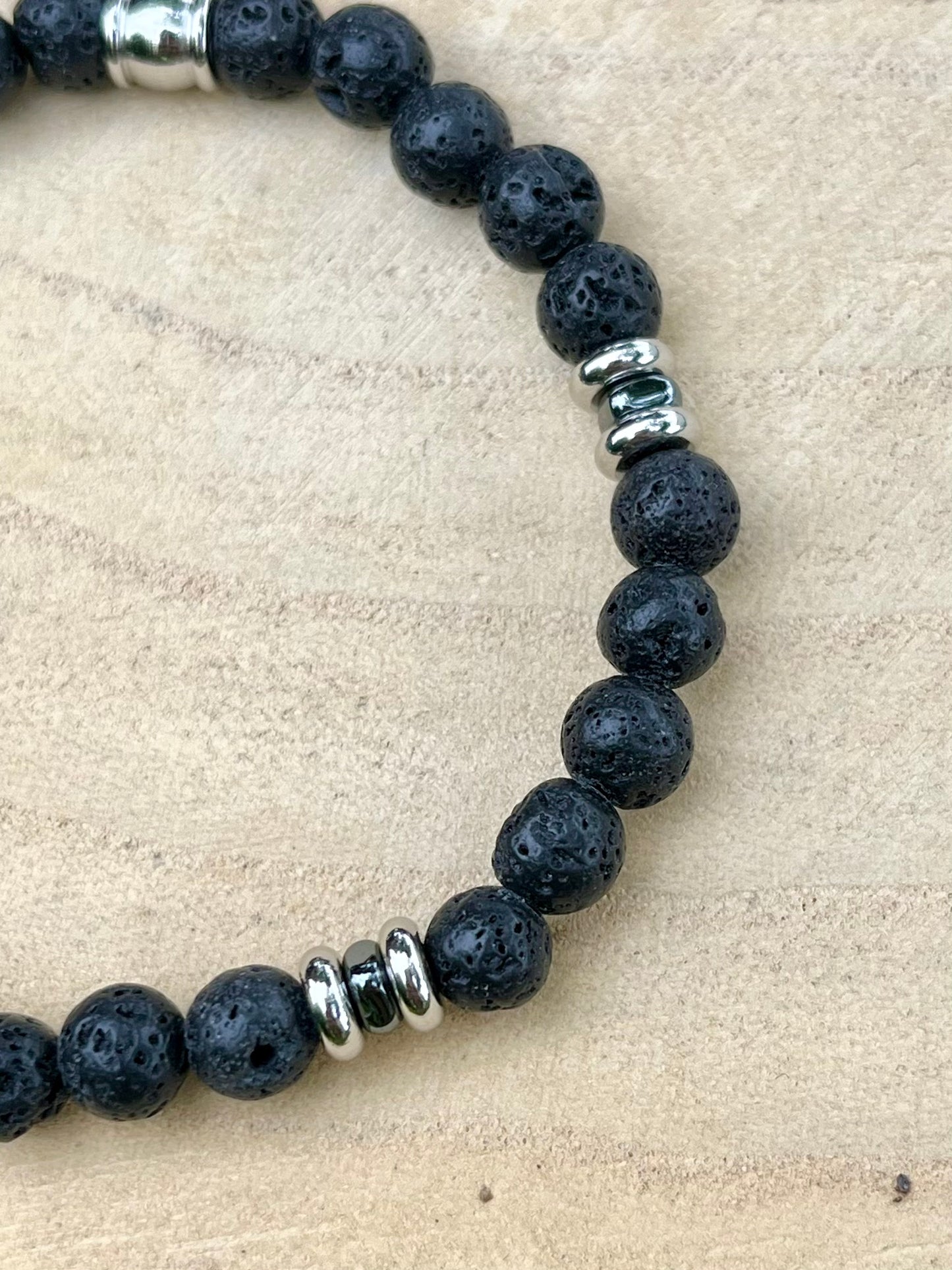Bracelet CAMILLE, avec pierres de Lave, exposé sur un rondin de bois.