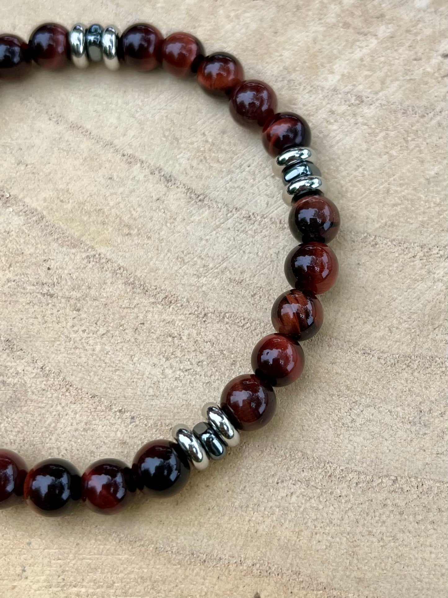 Bracelet CAMILLE, avec pierres d'Oeil de Taureau, exposé sur un rondin de bois.