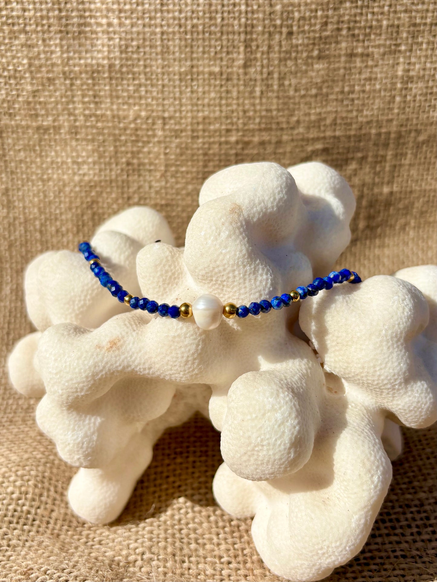 Bracelet ÈVE en Lapis-Lazuli et Perle de Culture posé sur du corail blanc, fond en toile de jute naturelle