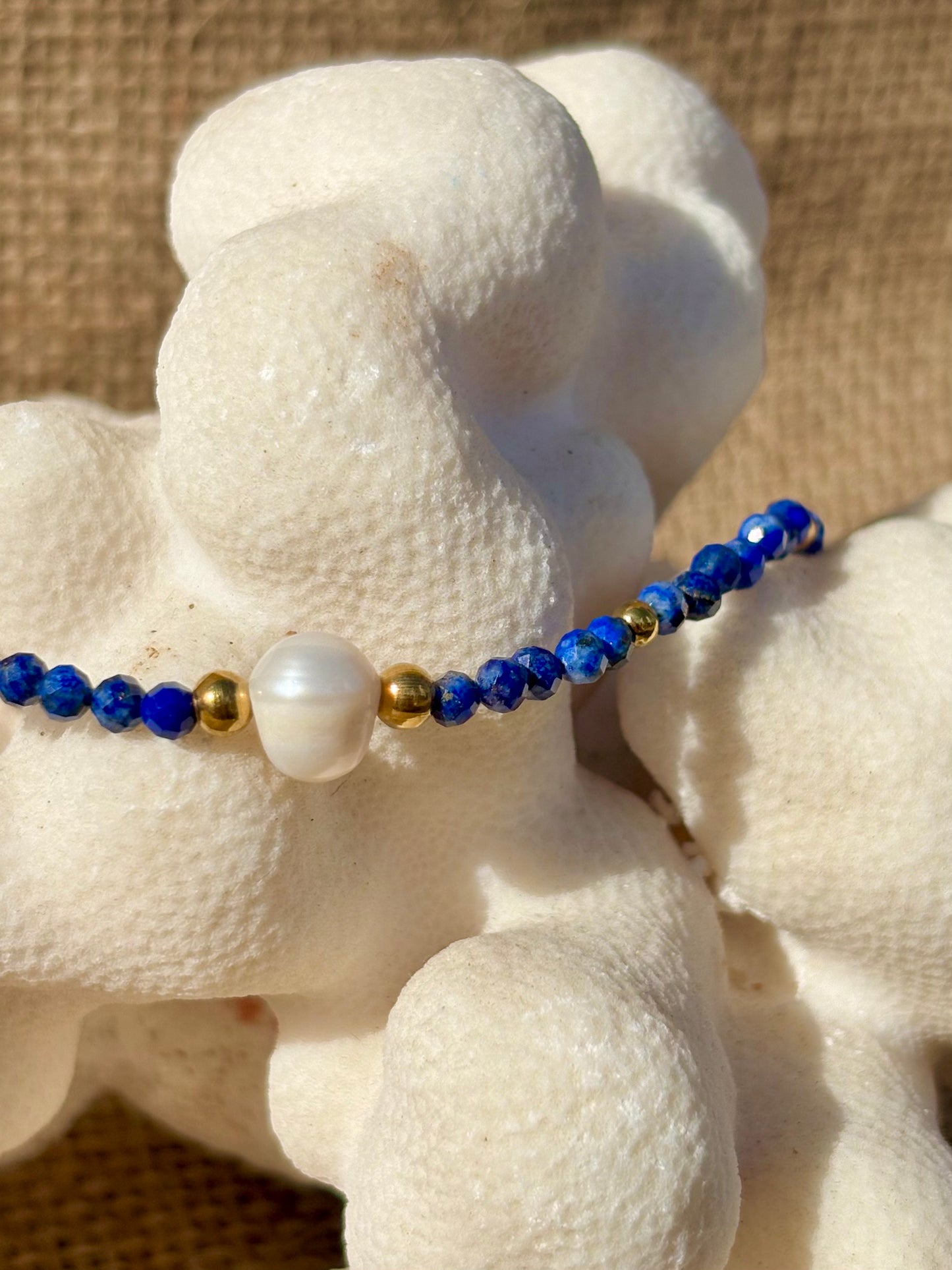Zoom sur la perle de culture centrale et les perles de Lapis-Lazuli du bracelet ÈVE, monté sur chaîne dorée en acier inoxydable.