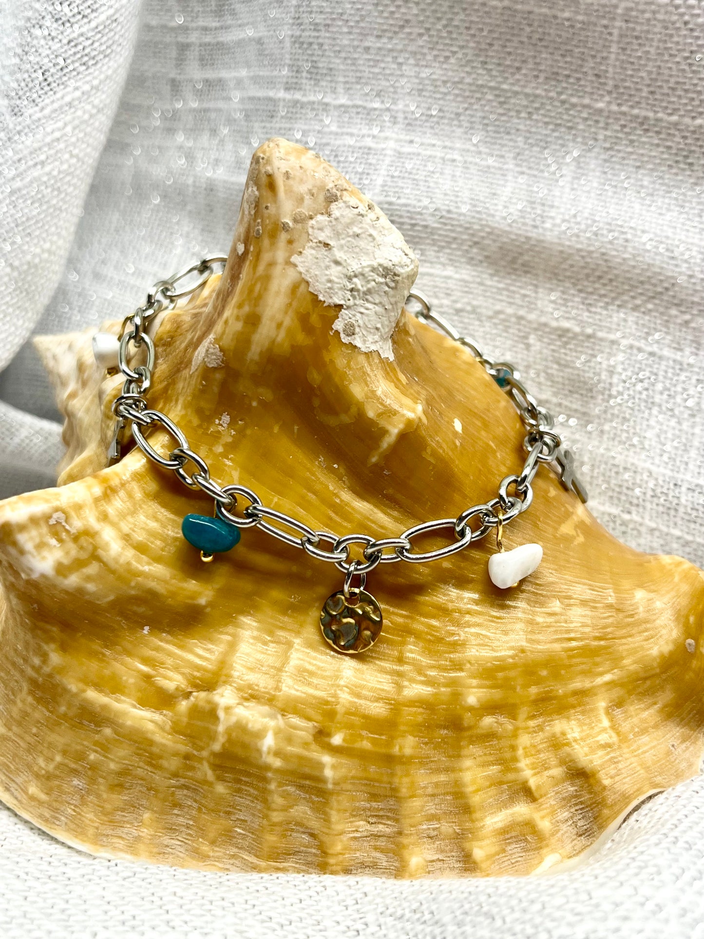 Bracelet JUDITH, avec pierres de Howlite et d'Apatite, exposé sur un coquillage.