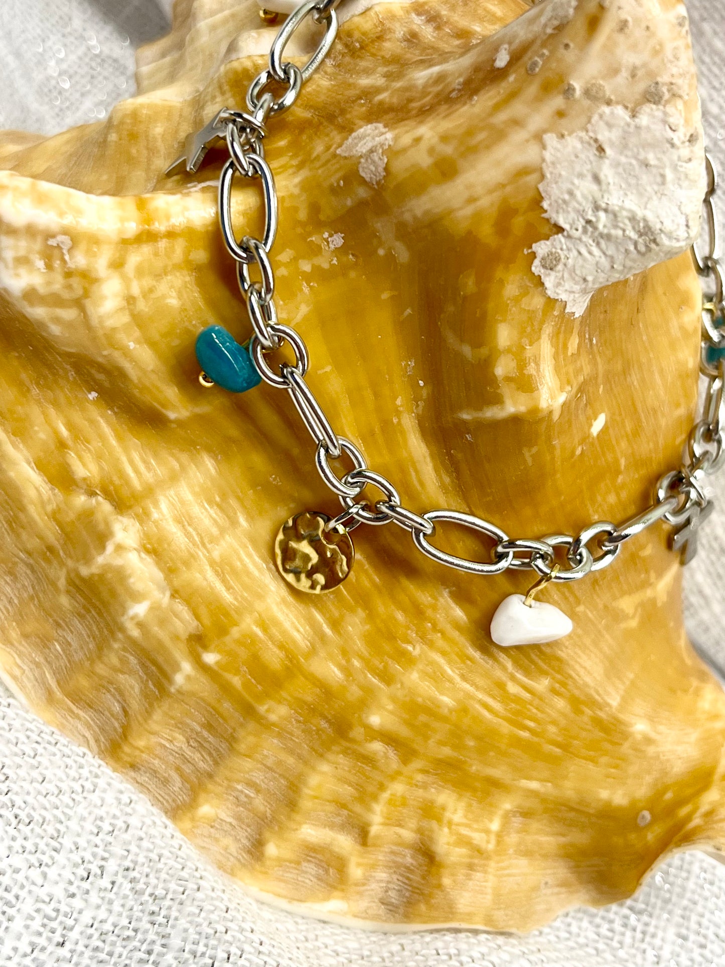 Bracelet JUDITH, avec pierres de Howlite et d'Apatite, exposé sur un coquillage.