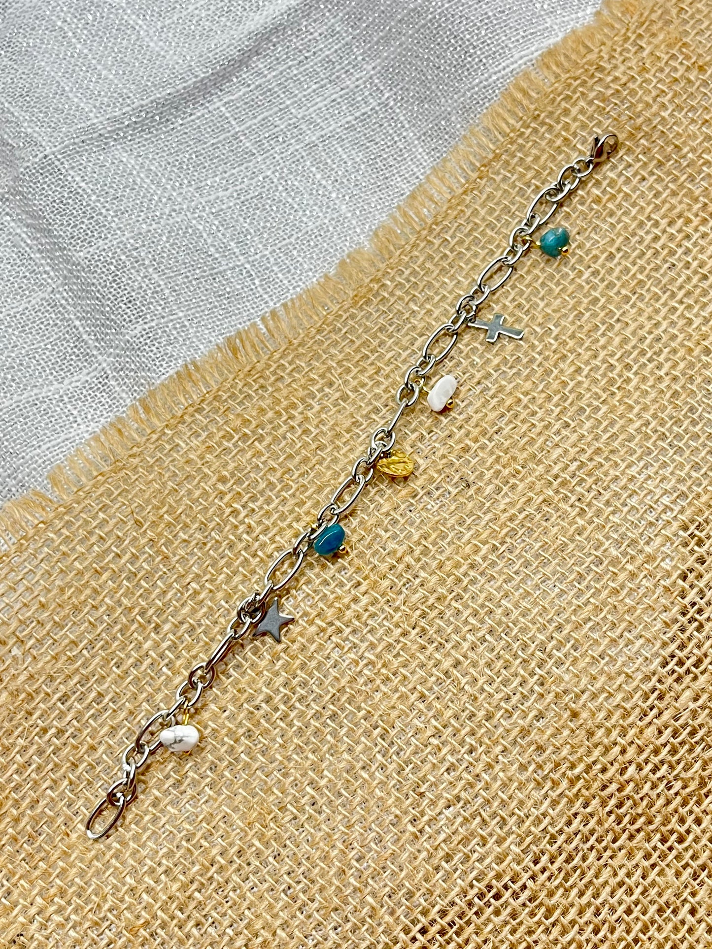 Bracelet JUDITH, avec pierres de Howlite et d'Apatite, exposé sur de la toile de jute.