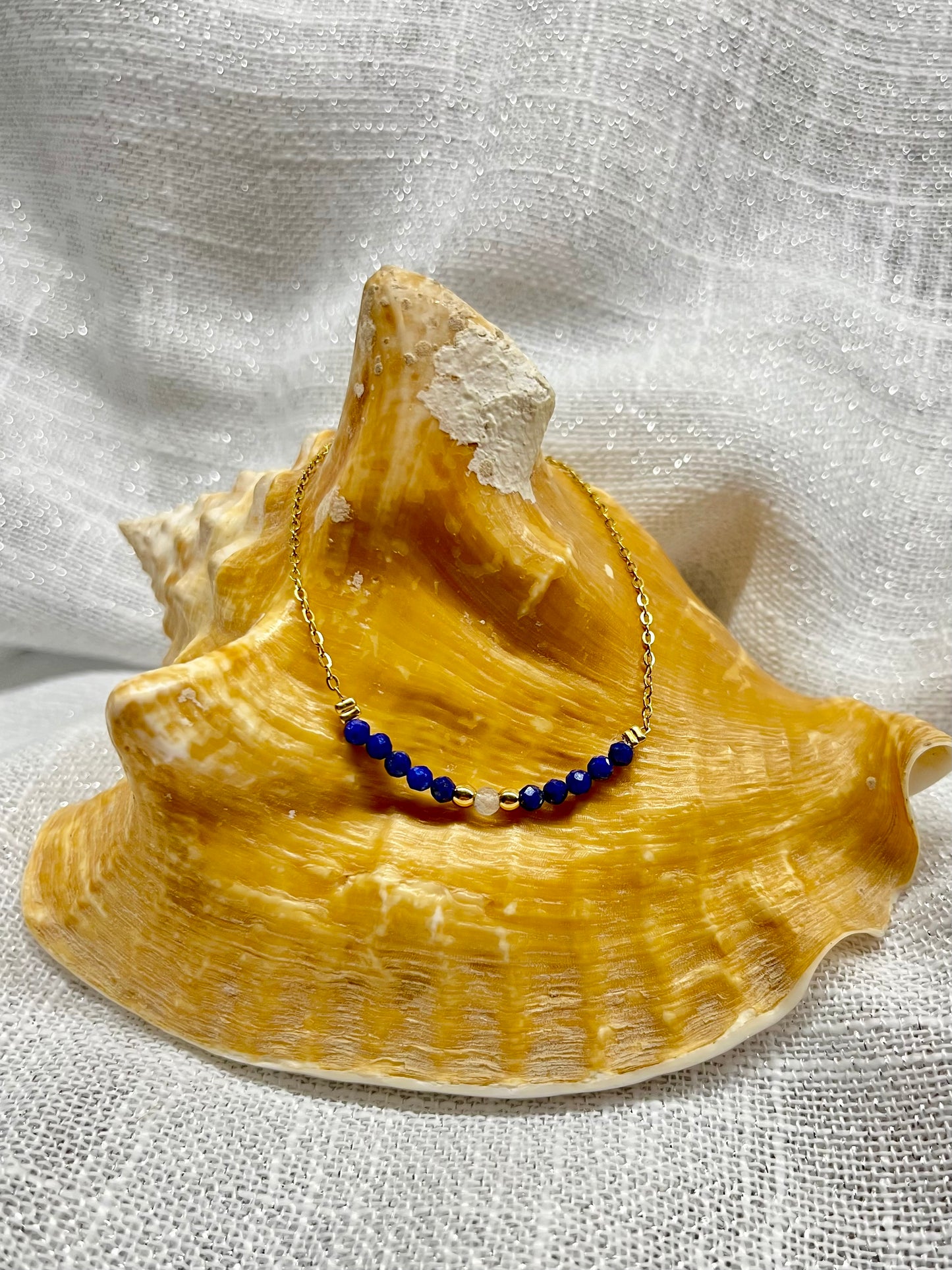 Collier JULIE, avec pierres de Lapis-Lazuli et de Labradorite, exposé sur un coquillage.