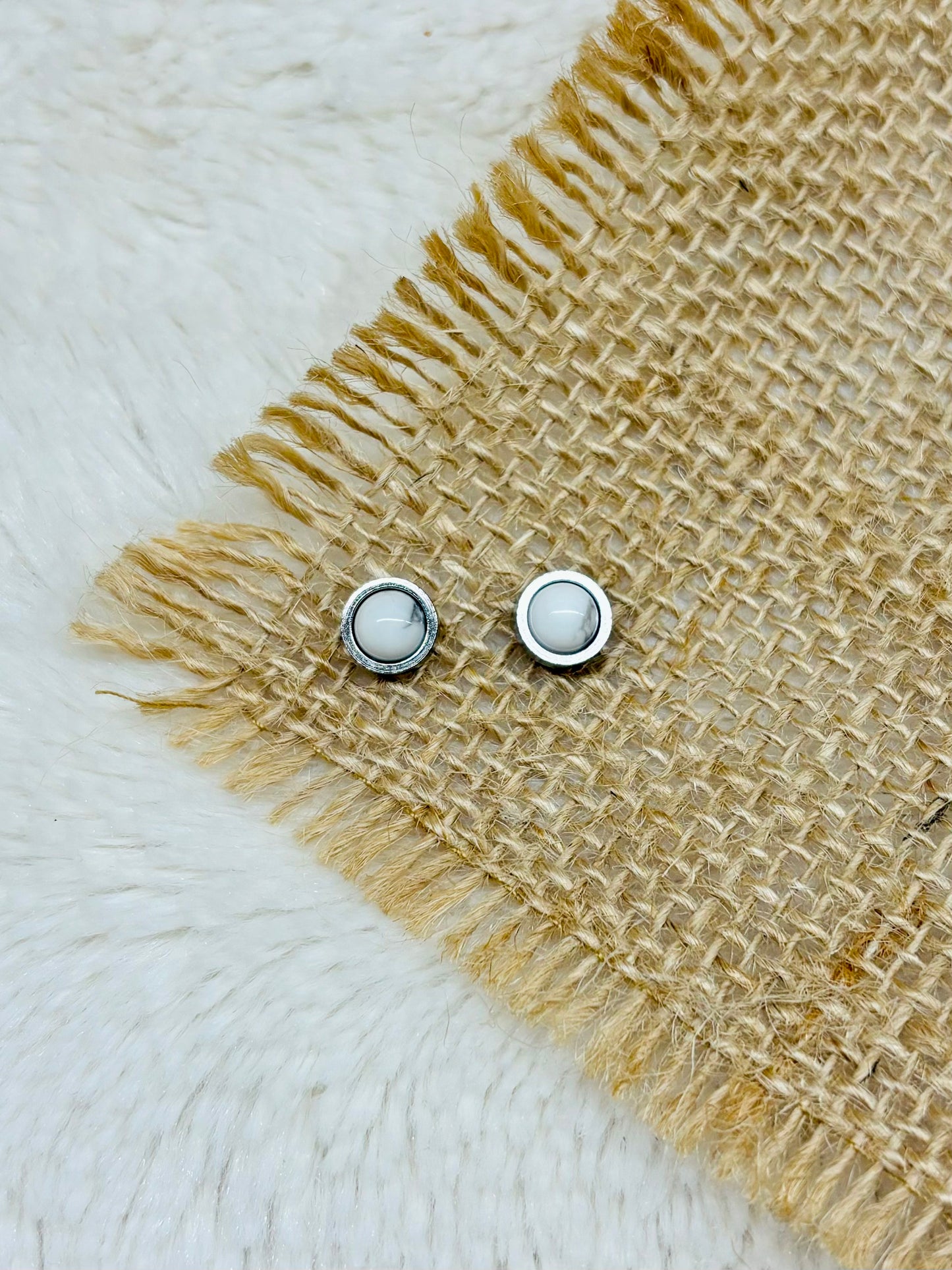 Boucles d'oreille LISE, avec pierre d'Howlite, exposées sur un fond en toile de jute.
