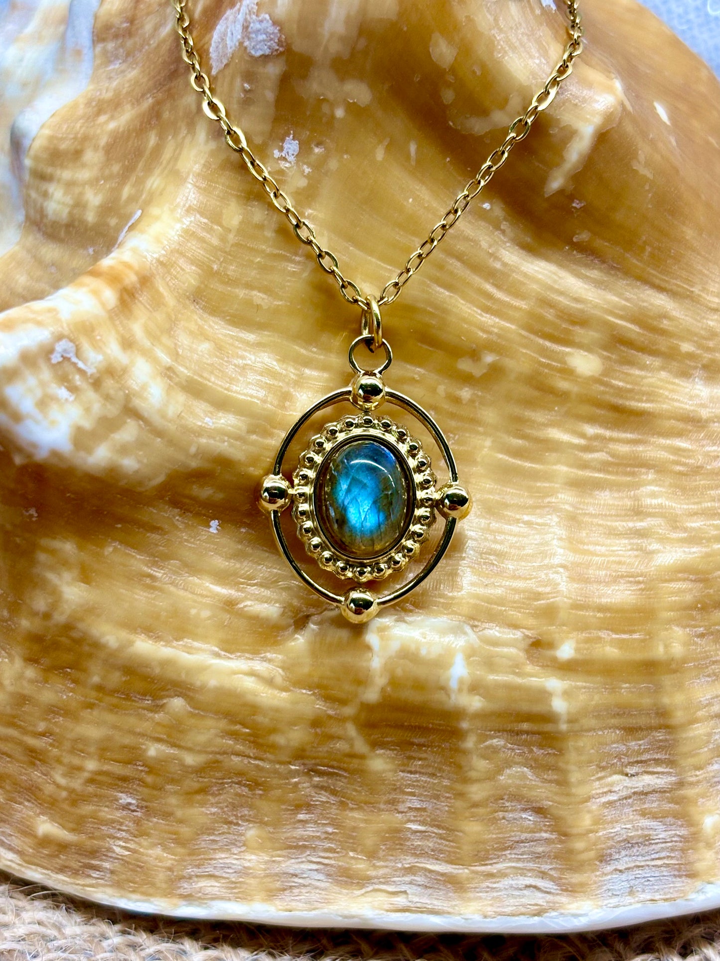 Collier LOUISA, avec pierre de Labradorite, exposé sur un coquillage.