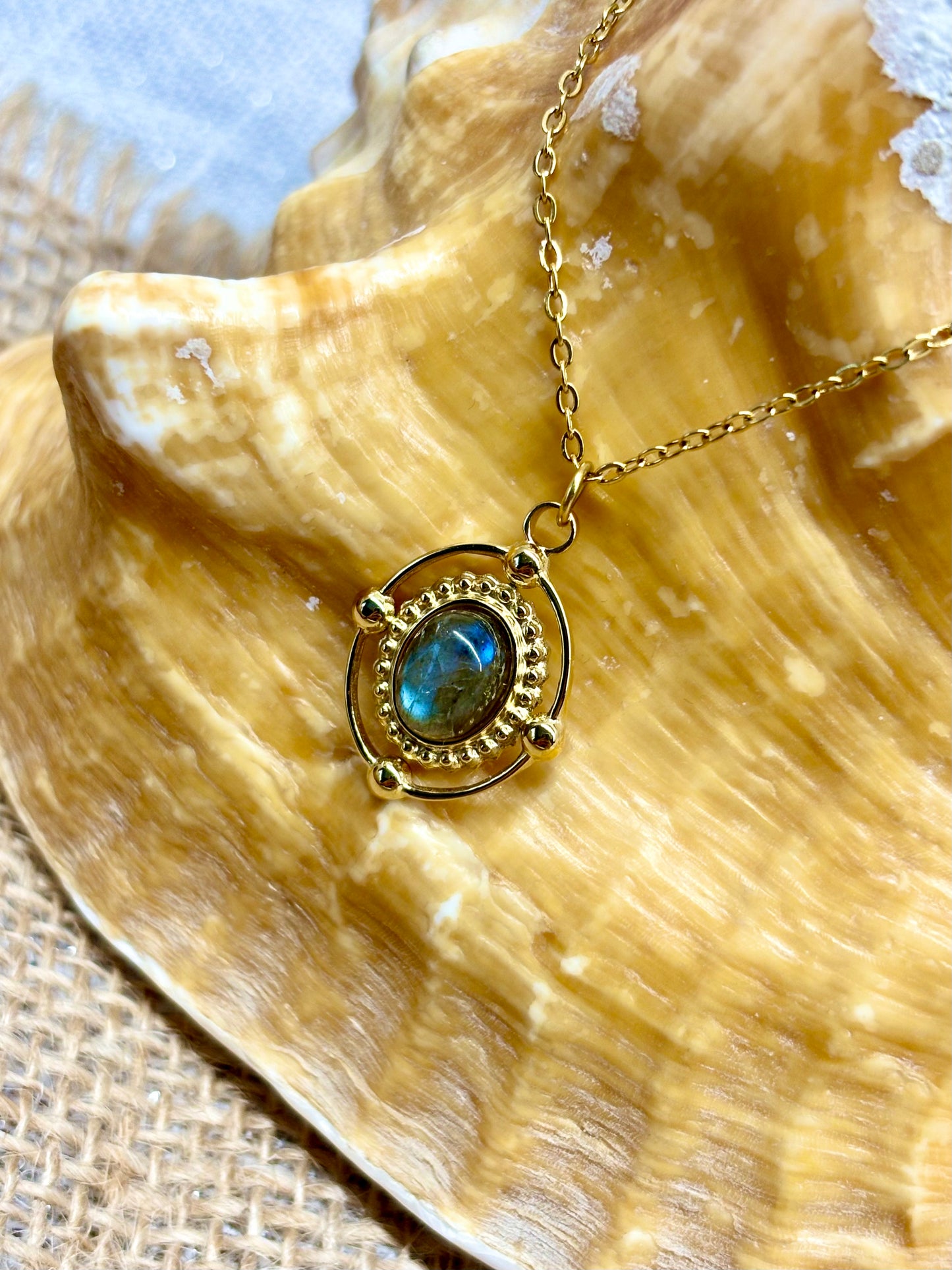 Collier LOUISA, avec pierre de Labradorite, exposé sur un coquillage.