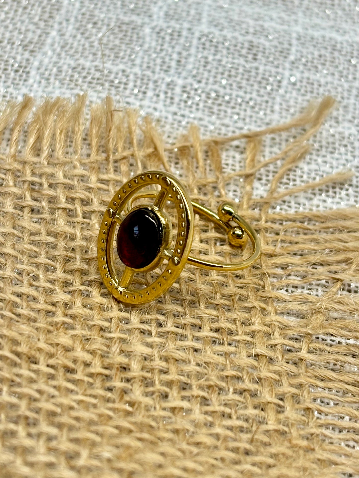 Bague LOUISE, avec pierre de Grenat, exposée sur de la toile de jute.