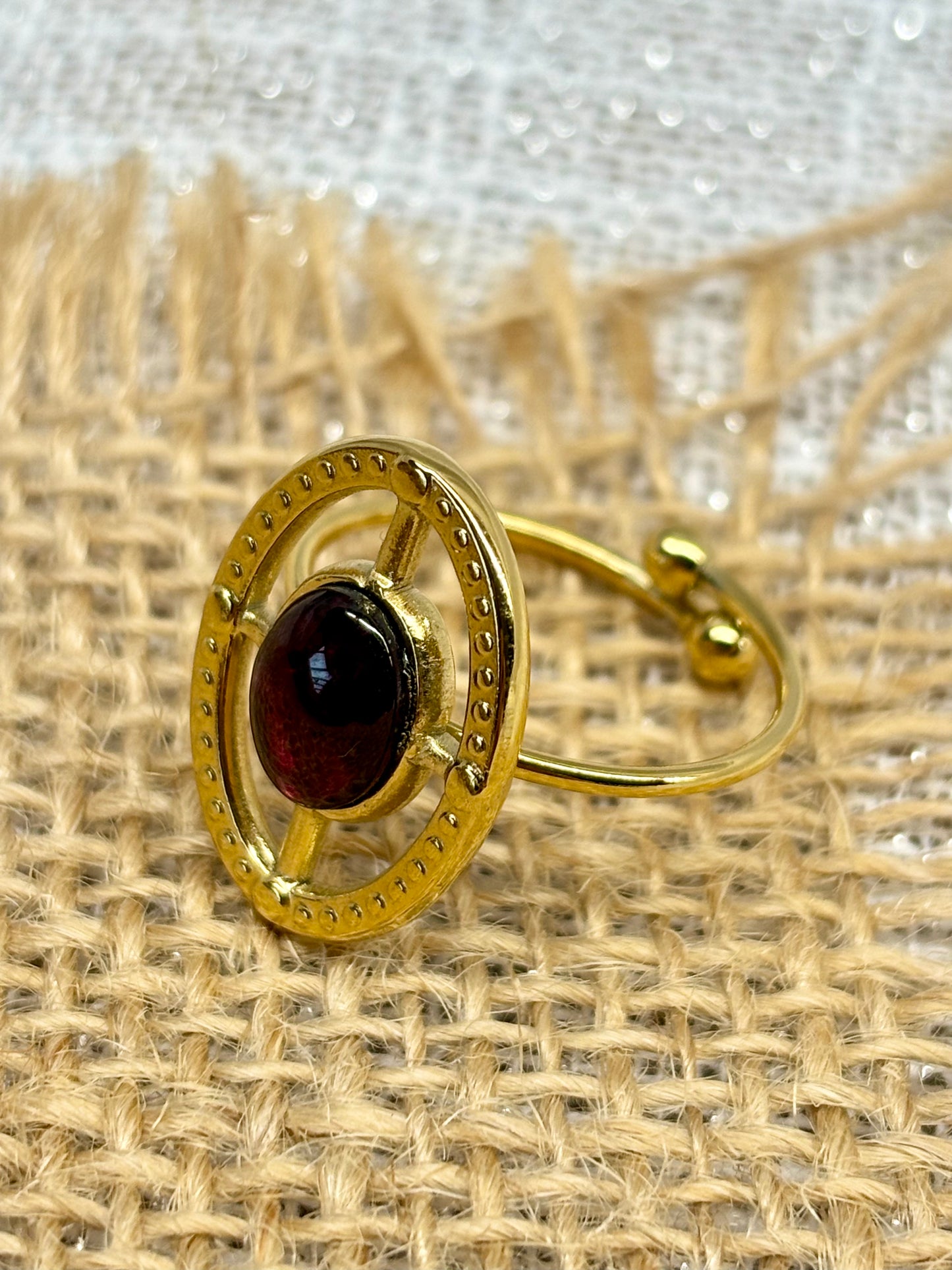 Bague LOUISE, avec pierre de Grenat, exposée sur de la toile de jute.
