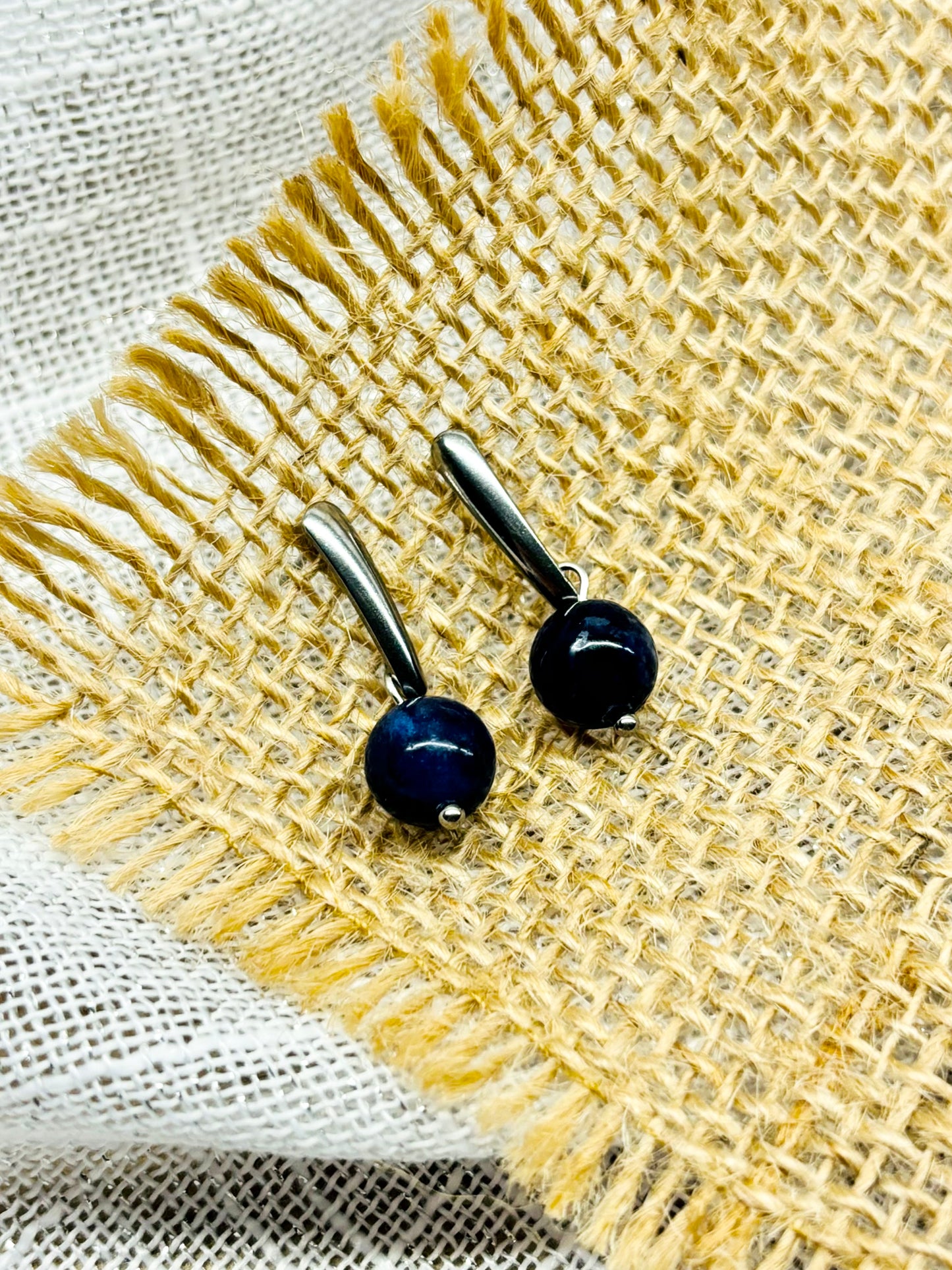Boucles d'oreille MADELEINE, avec pierre de Sodalite, exposées sur de la toile de jute.