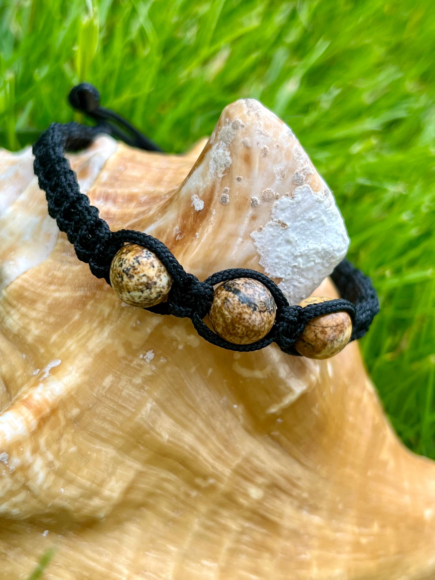 Bracelet MAËL, avec pierres de Jaspe Paysage, exposé sur un coquillage.