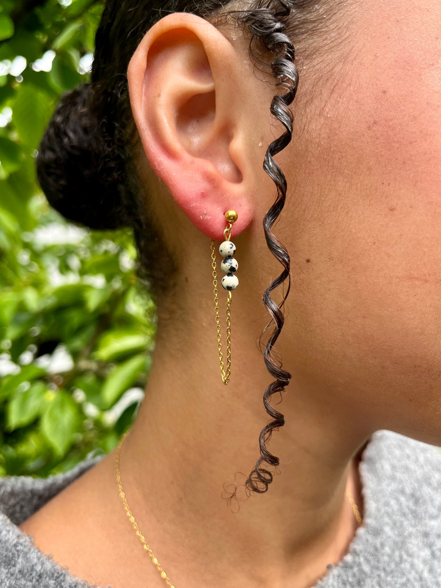 Boucles d'oreille MALIA, de couleur dorée avec pierre de Jaspe Dalmatien, portées.