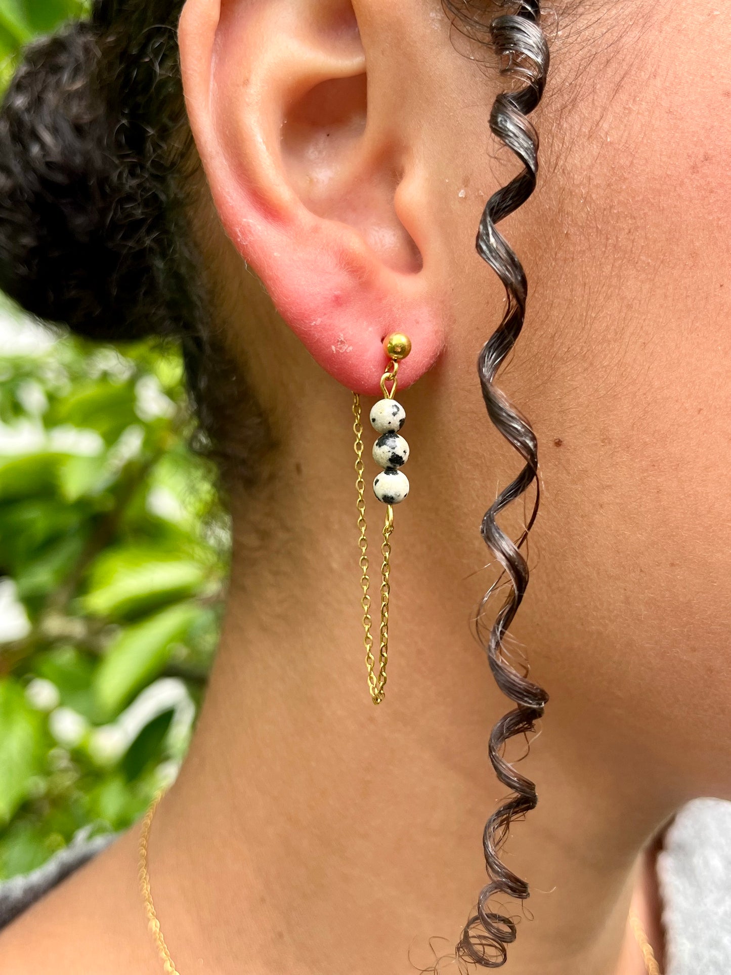 Boucles d'oreille MALIA, de couleur dorée avec pierre de Jaspe Dalmatien, portées.