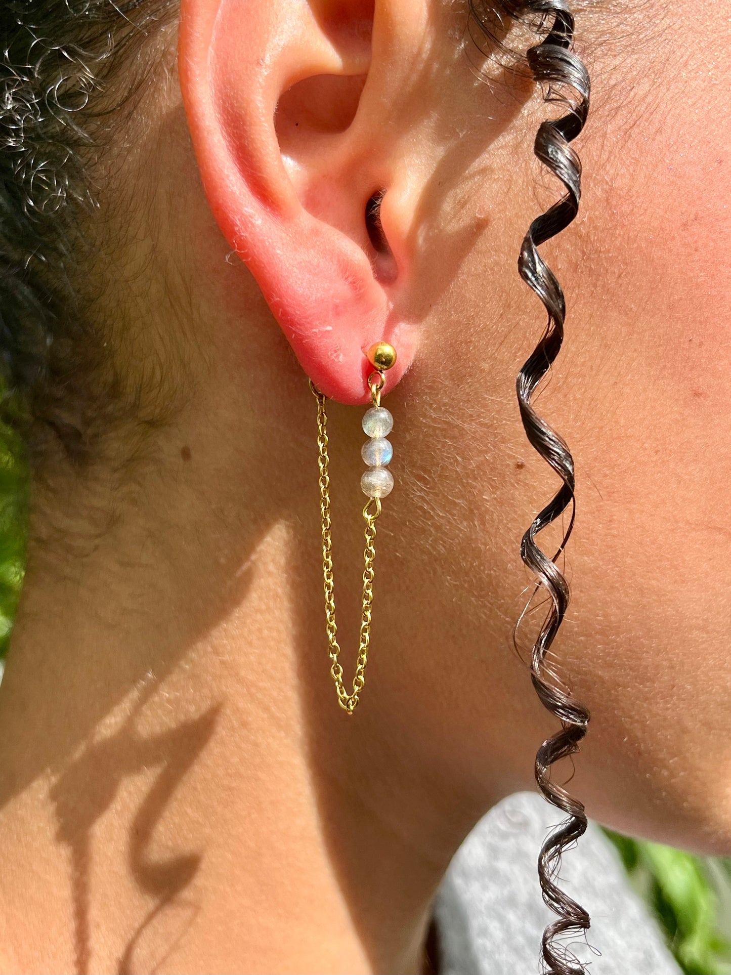 Boucles d'oreille MALIA, de couleur dorée avec pierres de Labradorite, portées.