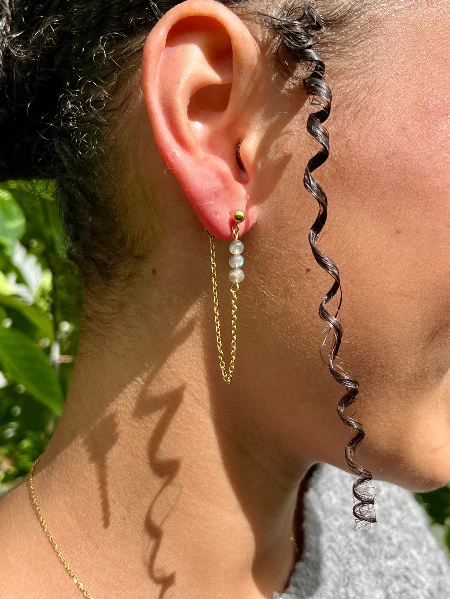 Boucles d'oreille MALIA, de couleur dorée avec pierres de Labradorite, portées.