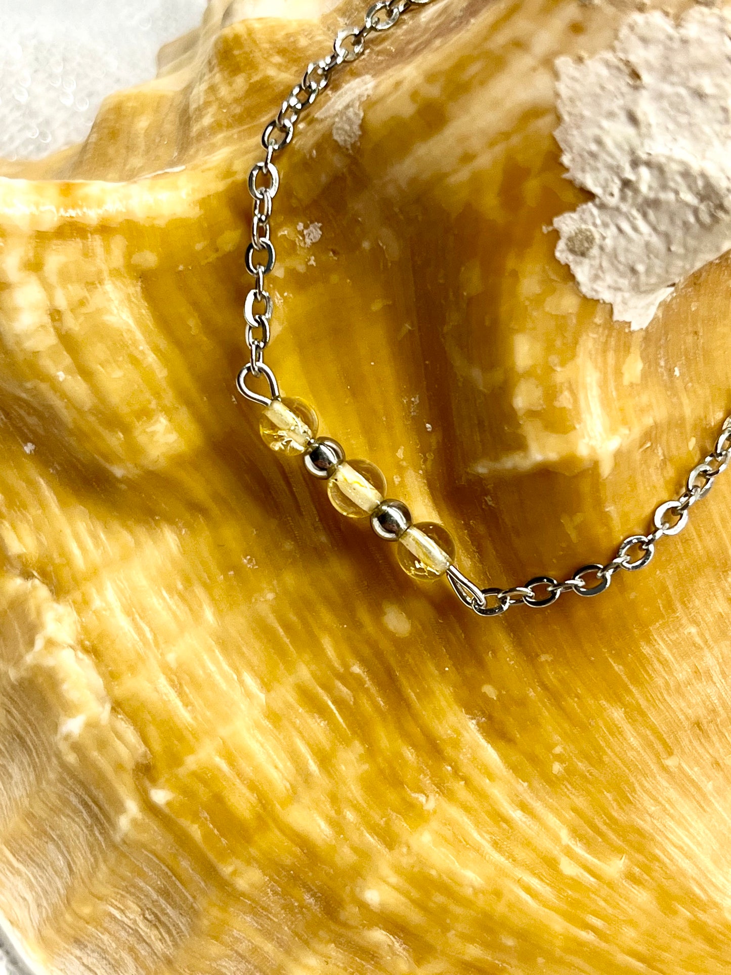 Bracelet MALIA, de couleur argent avec pierres de Citrine, exposé sur un coquillage.