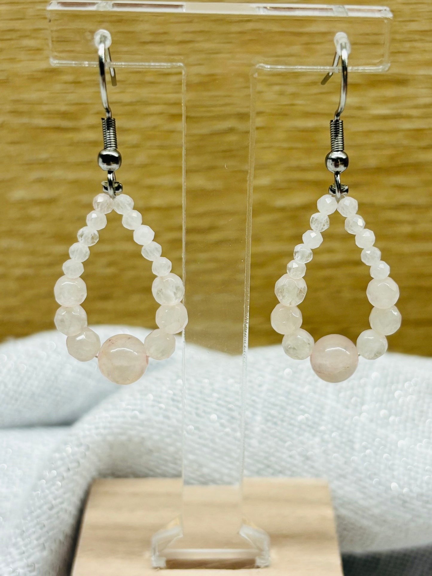 Boucles d'oreille SIMONA, avec pierres de Quartz Rose, exposées sur un fond en bois.