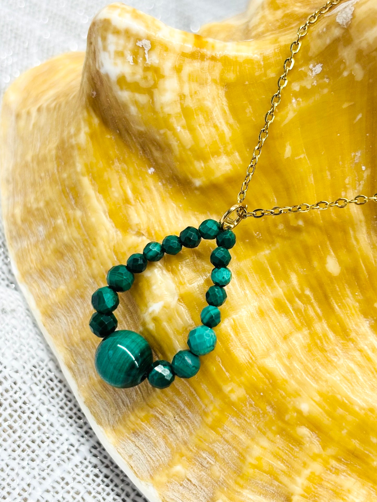 Collier SIMONA, avec pierres de Malachite, exposé sur un coquillage.