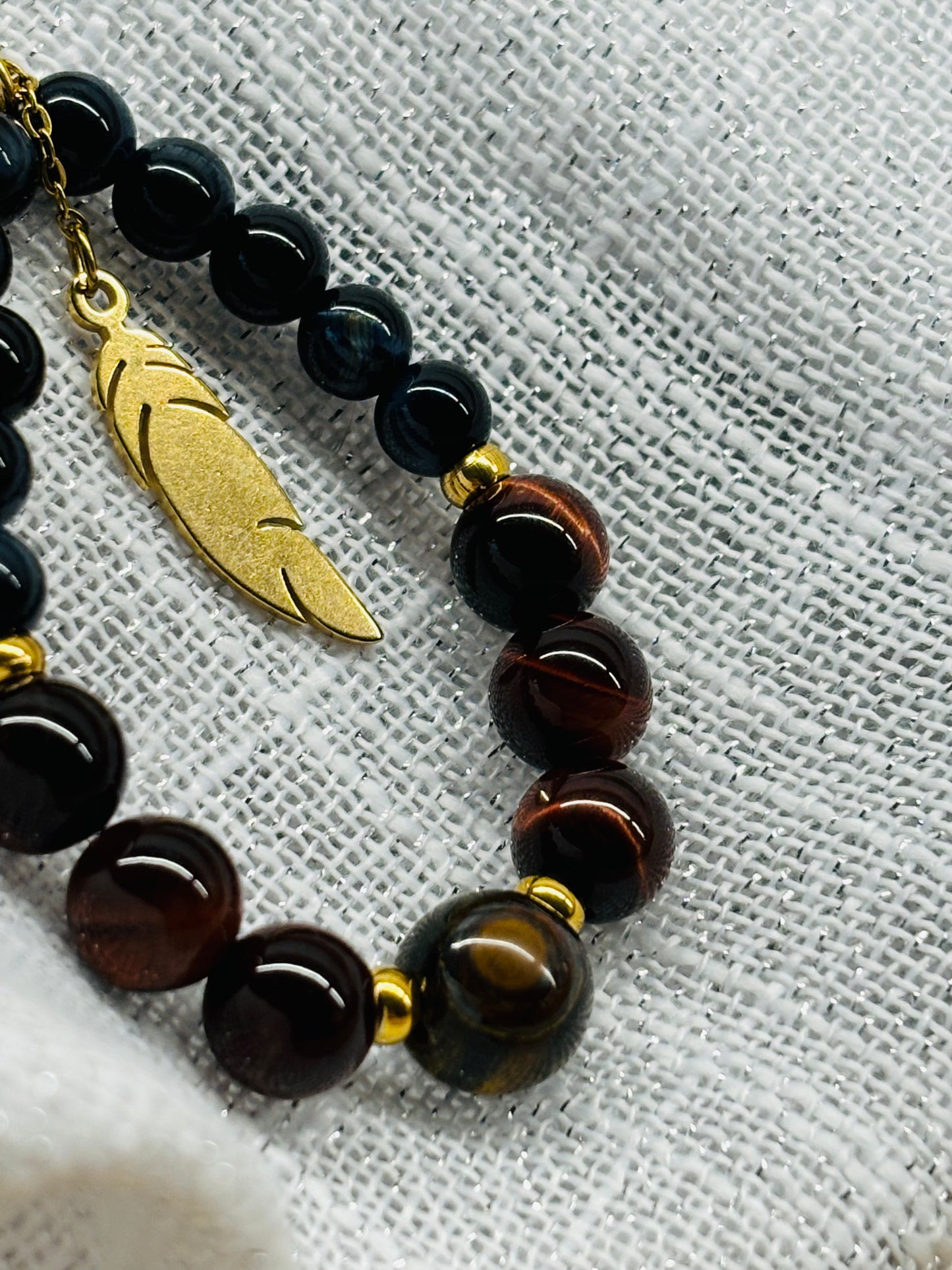 Collier SIMONE, avec pierre d'Oeil de Tigre, de Taureau et de Faucon, exposé sur un fond en lin.