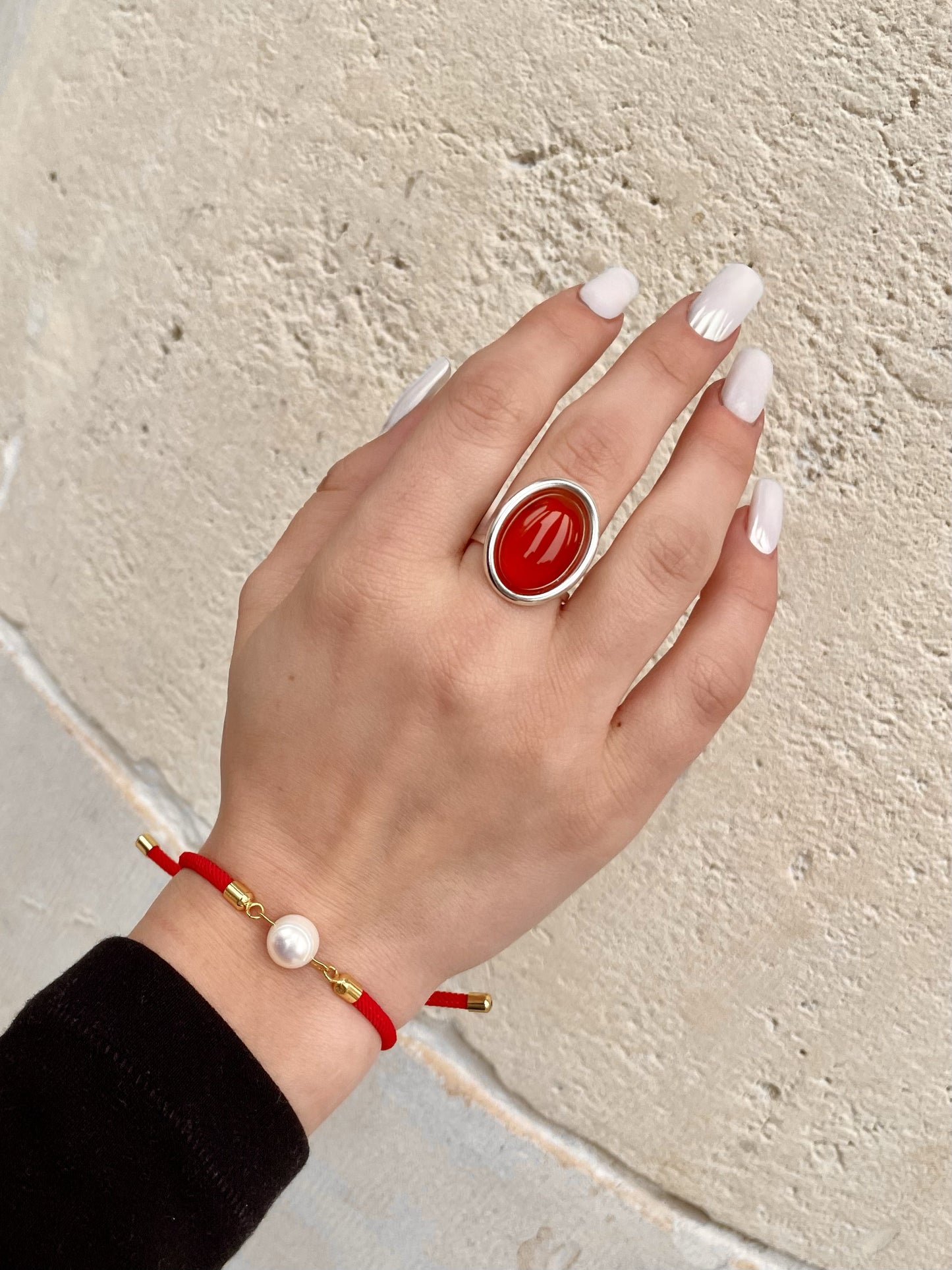 Bague THÉA, en argent et pierre de Cornaline, portée sur une main de femme.