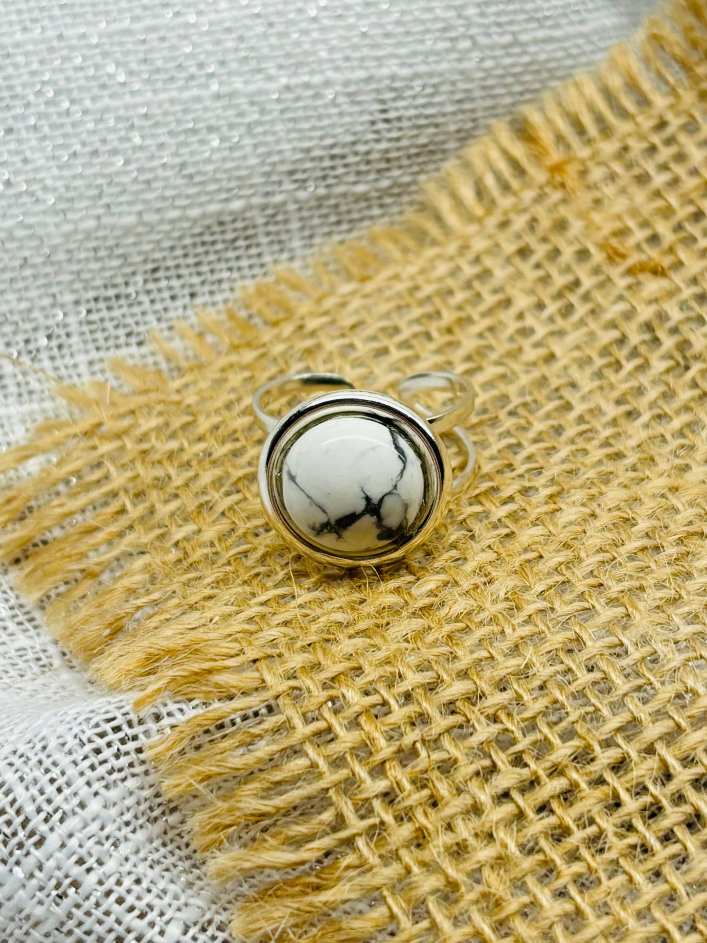 Bague THÉA, en argent et pierre d'Howlite, sur un fond en lin et toile de jute.