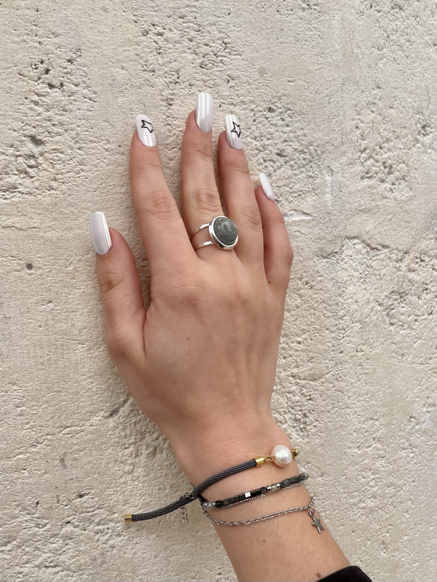 Bague THÉA, en argent et pierre de Labradorite, portée sur une main de femme.