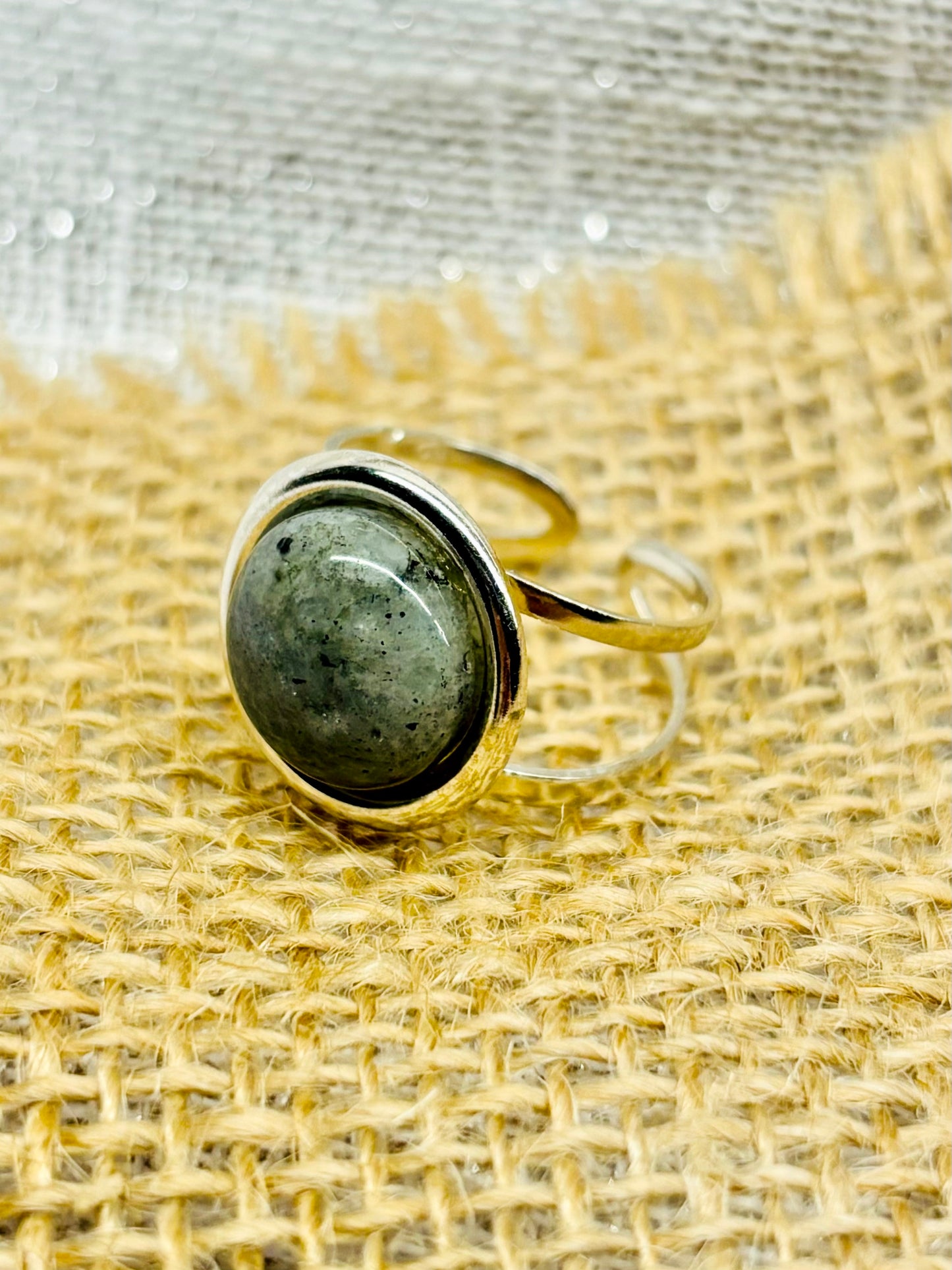Bague THÉA, en argent et pierre de Labradorite, sur un fond de lin et toile de jute.