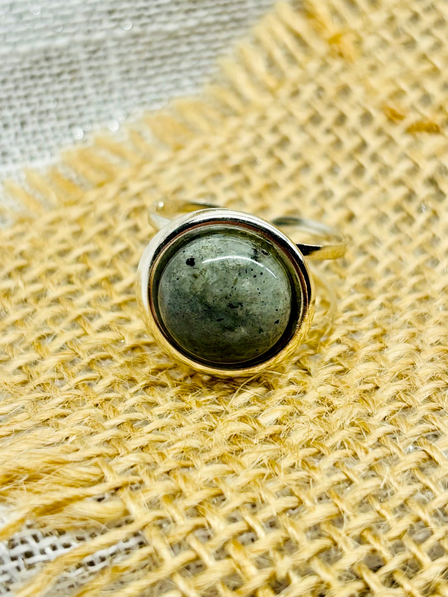 Bague THÉA, en argent et pierre de Labradorite, sur un fond de lin et toile de jute.