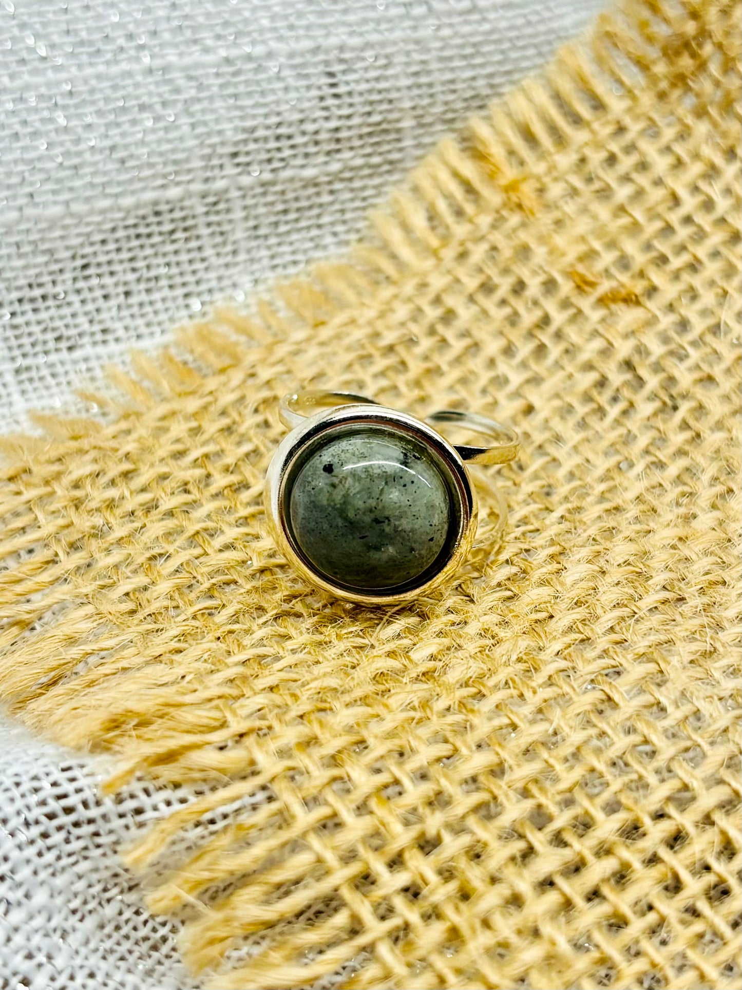 Bague THÉA, en argent et pierre de Labradorite, sur un fond de lin et toile de jute.