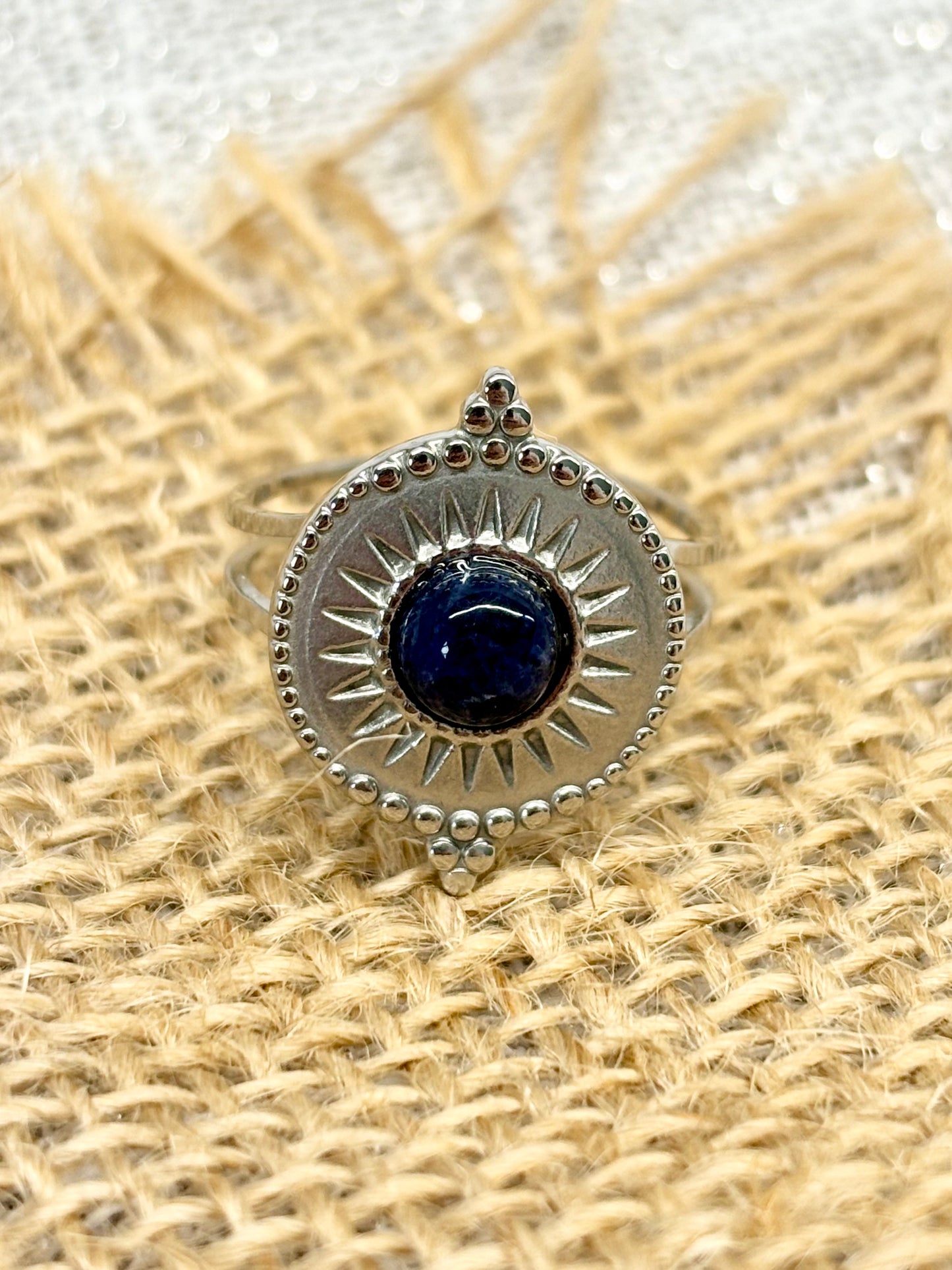 Bague ZÉLIE en acier inoxydable argent et pierre de Sodalite, exposé sur de la toile de jute et un fond en lin.