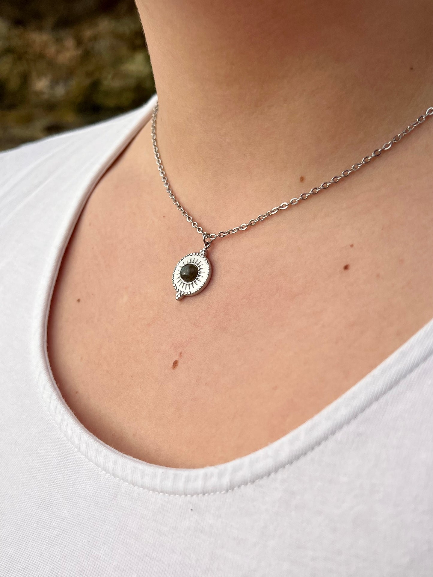 Collier ZÉLIE en acier inoxydable argent et pierre de Labradorite, porté par une fille dans les rochers.