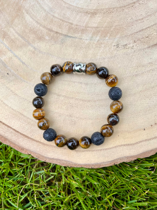 Bracelet ADAM, avec pierre d'Oeil de Tigre et Pierre de Lave, exposé sur un rondin de bois.