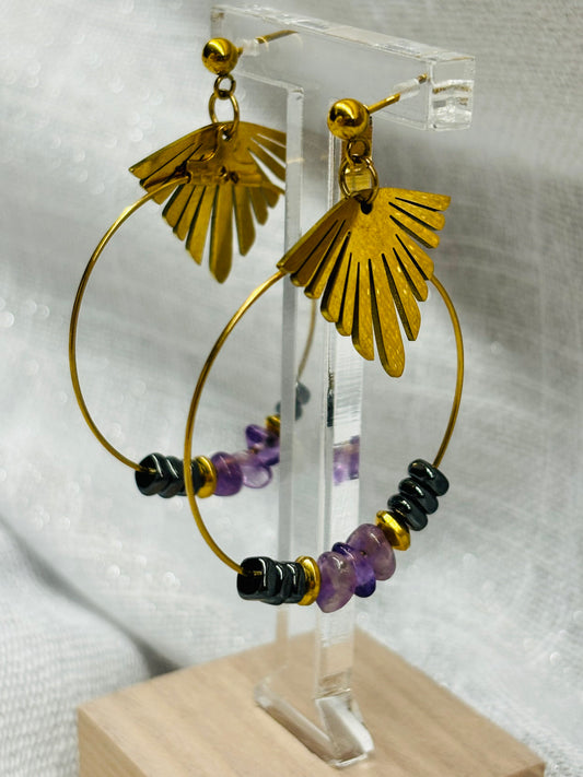 Paire de boucles d'oreille Créoles en acier inoxydable doré, avec pierres d'Améthystes et d'Hématites, exposés sur un support.