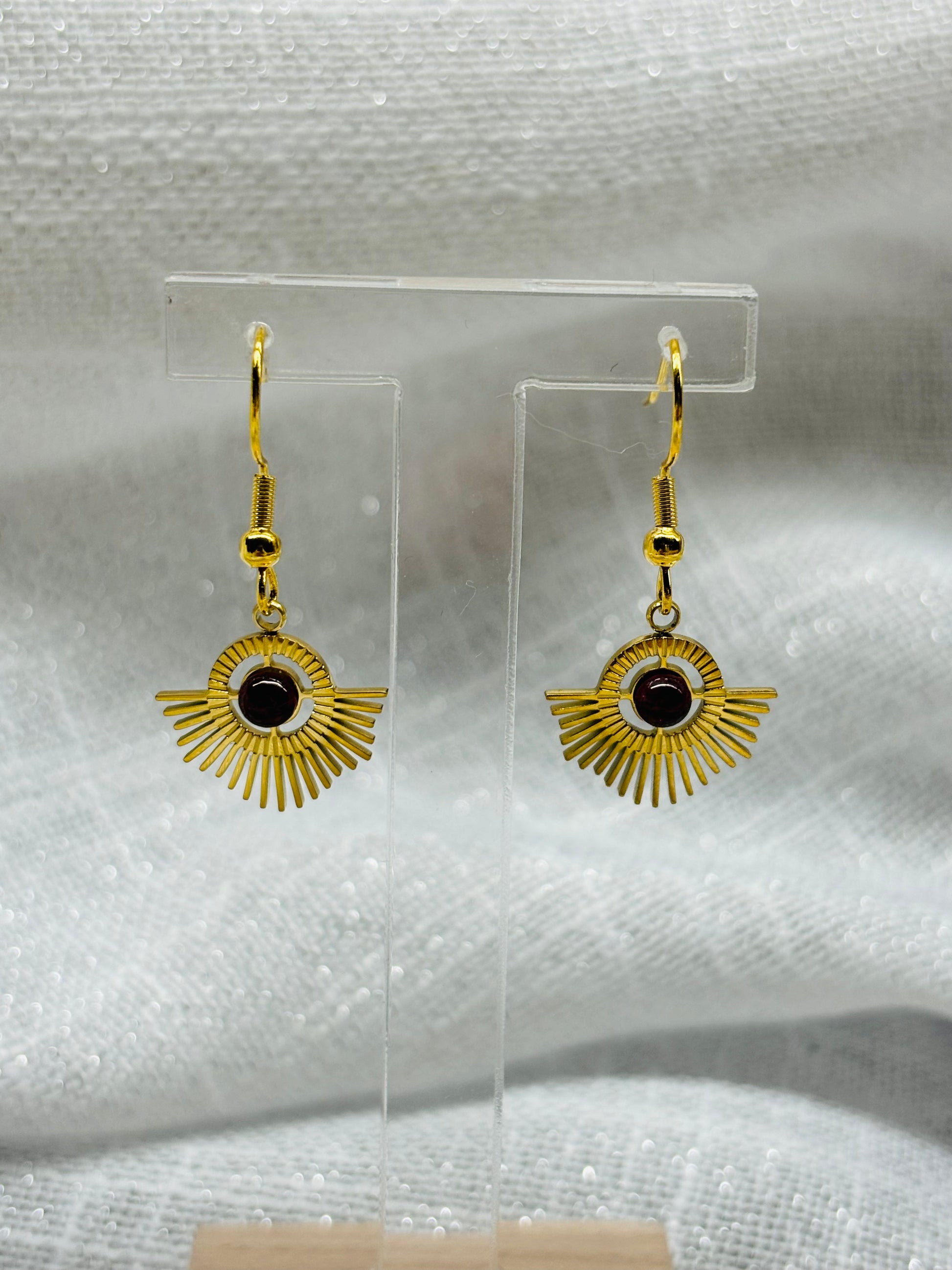 Boucles d'oreille ALLY, avec pierre de Grenat, exposées sur un fond en lin.