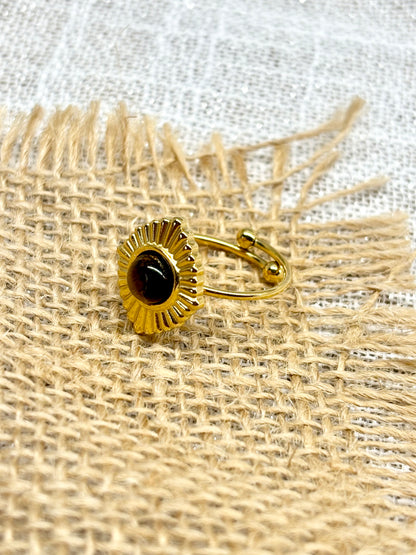 Bague ALYSÉE, de couleur dorée avec pierre d'Oeil de Tigre, exposée sur un fond en lin et toile de jute.