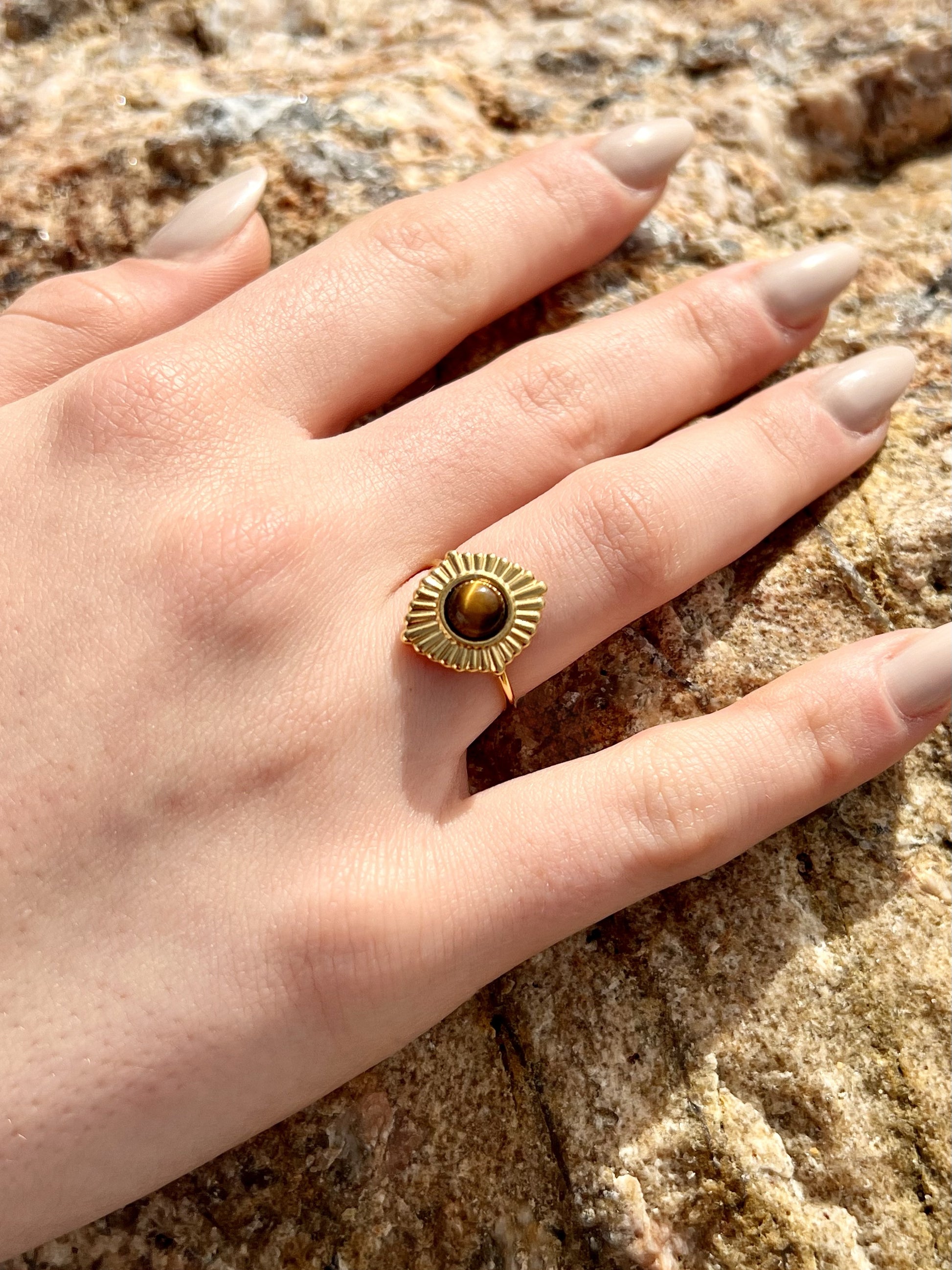 Bague ALYSÉE, de couleur dorée avec pierre d'Oeil de Tigre, portée sur une main de femme.