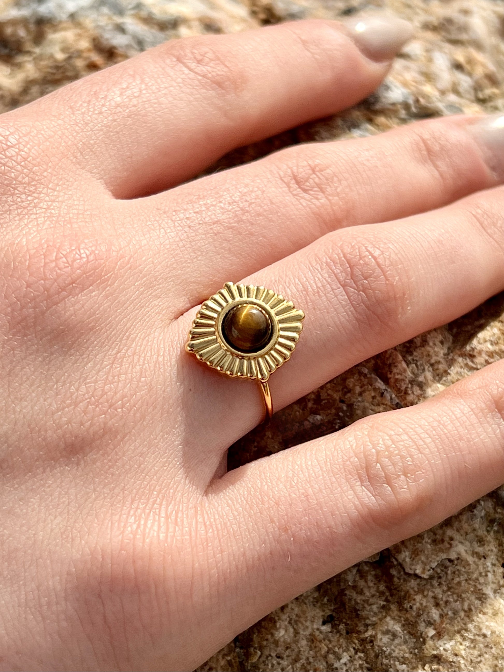 Bague ALYSÉE, de couleur dorée avec pierre d'Oeil de Tigre, portée sur une main de femme.