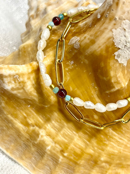 Bracelet ARIANA, avec pierre d'Amazonite, de Grenat et Perle de Culture, exposé sur un coquillage.